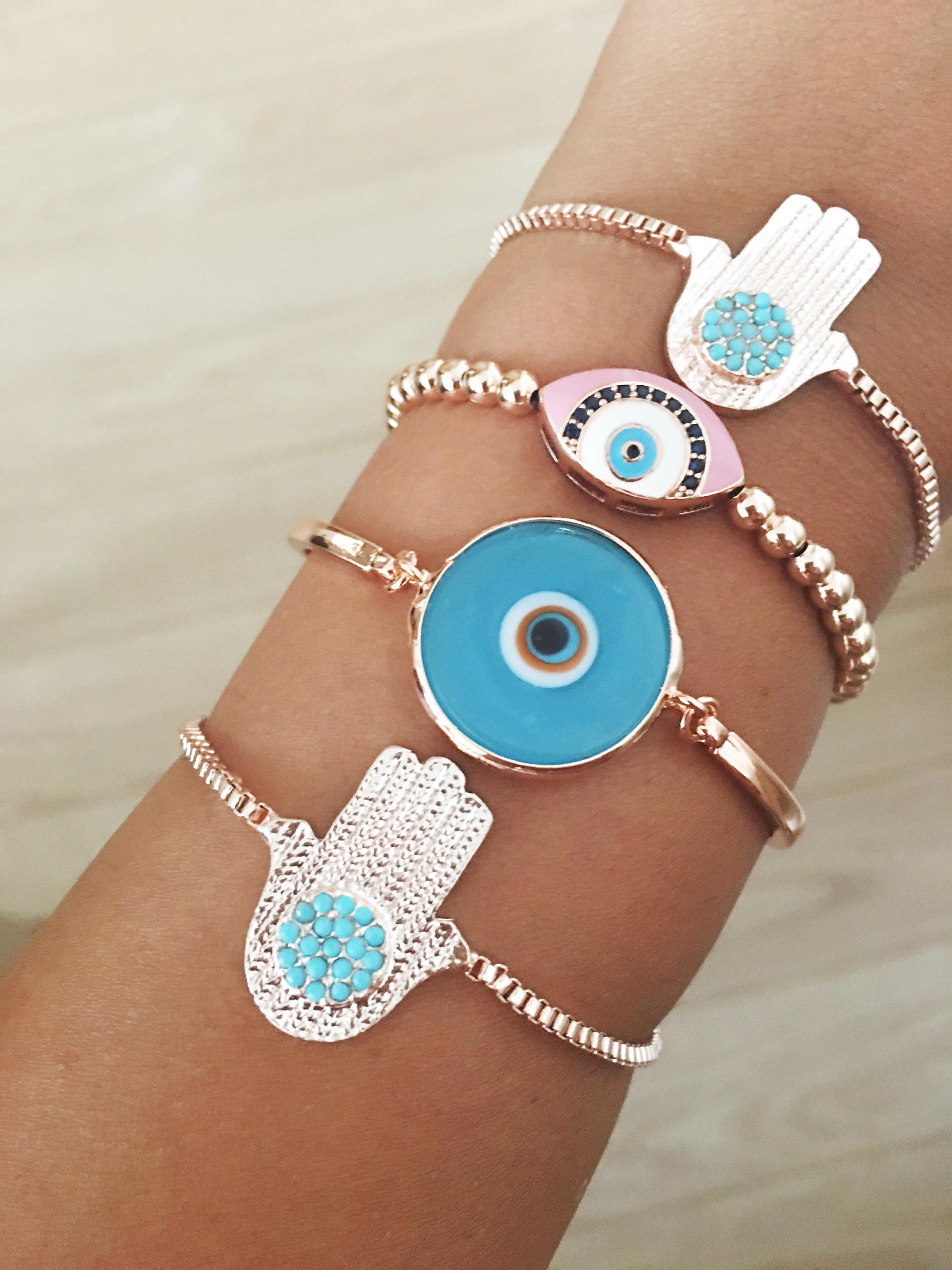 A beautiful rose gold bracelet set featuring an evil eye hamsa design, showcasing multiple bracelets with intricate details and adjustable features.