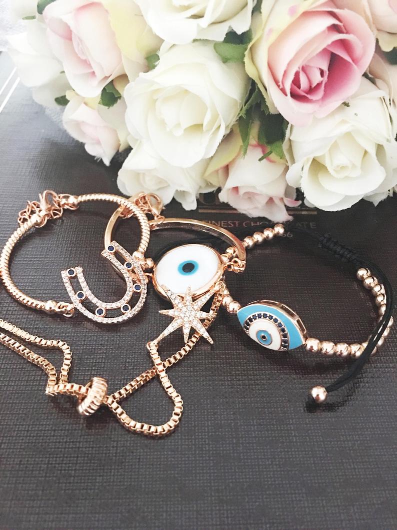 A beautiful Rose Gold Bracelet Set featuring a Murano Evil Eye bracelet, star bracelet, and horseshoe bracelet, showcasing intricate designs and craftsmanship.