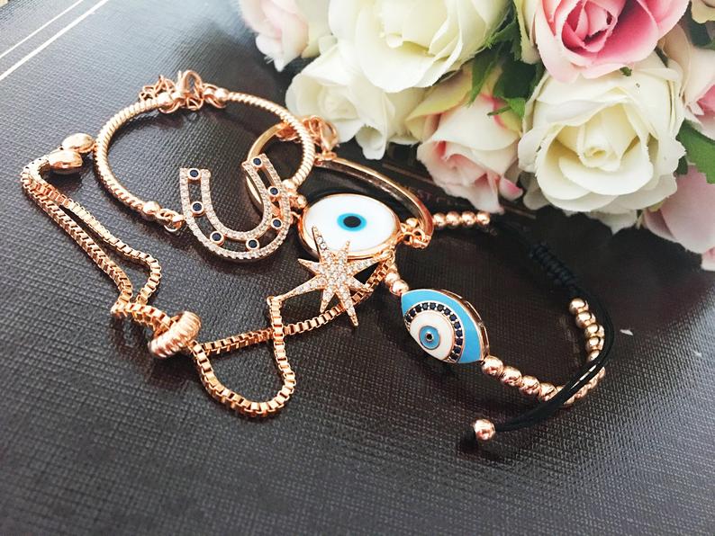 A beautiful Rose Gold Bracelet Set featuring a Murano Evil Eye bracelet, star bracelet, and horseshoe bracelet, showcasing intricate designs and craftsmanship.