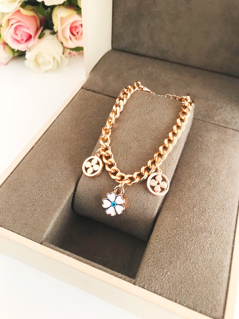 A beautiful rose gold chain bracelet featuring a clover charm and an evil eye, showcasing its elegant design and craftsmanship.