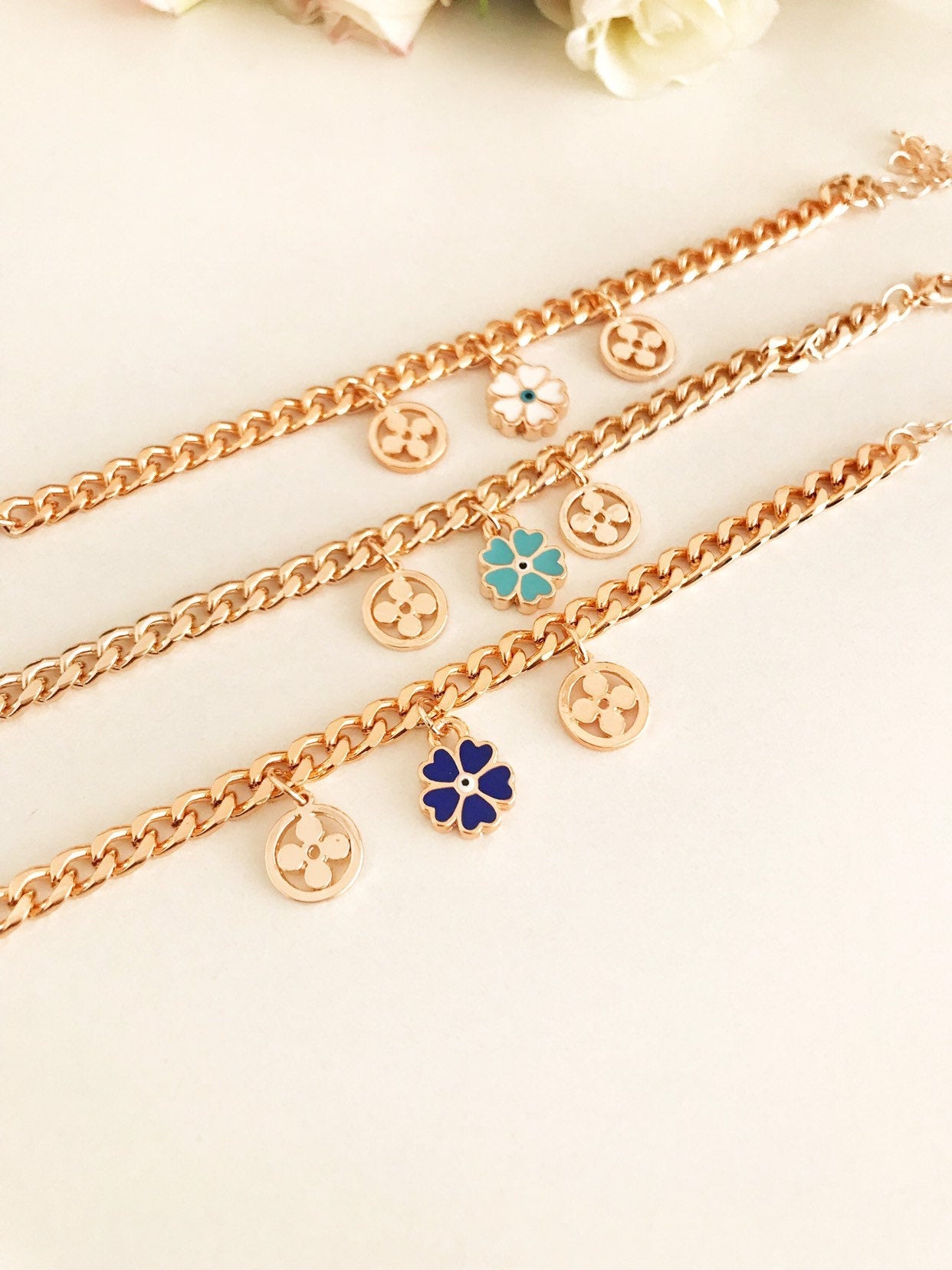 A beautiful rose gold chain bracelet featuring a clover charm and an evil eye, showcasing its elegant design and craftsmanship.