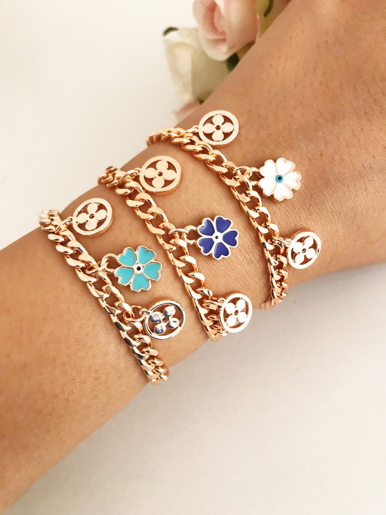 A beautiful rose gold chain bracelet featuring a clover charm and an evil eye, showcasing its elegant design and craftsmanship.