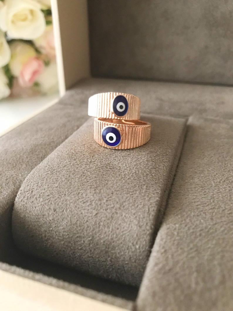 A dainty rose gold adjustable ring featuring an oval blue evil eye bead, symbolizing protection and style.