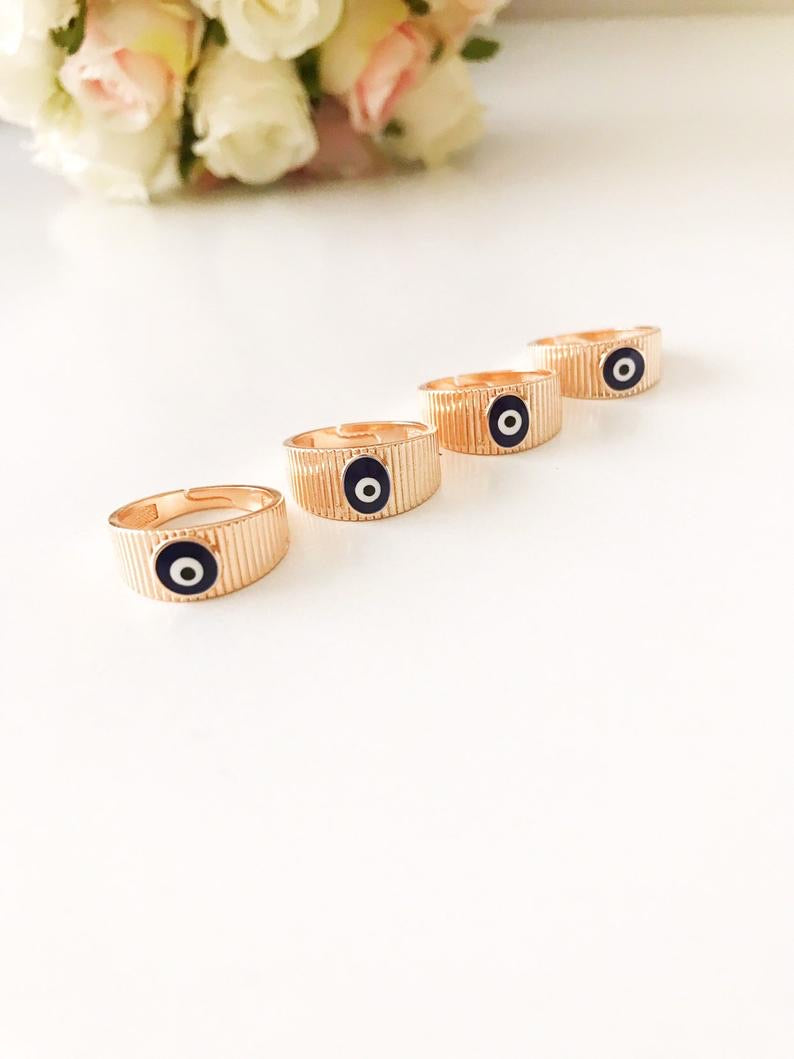 A dainty rose gold adjustable ring featuring an oval blue evil eye bead, symbolizing protection and style.