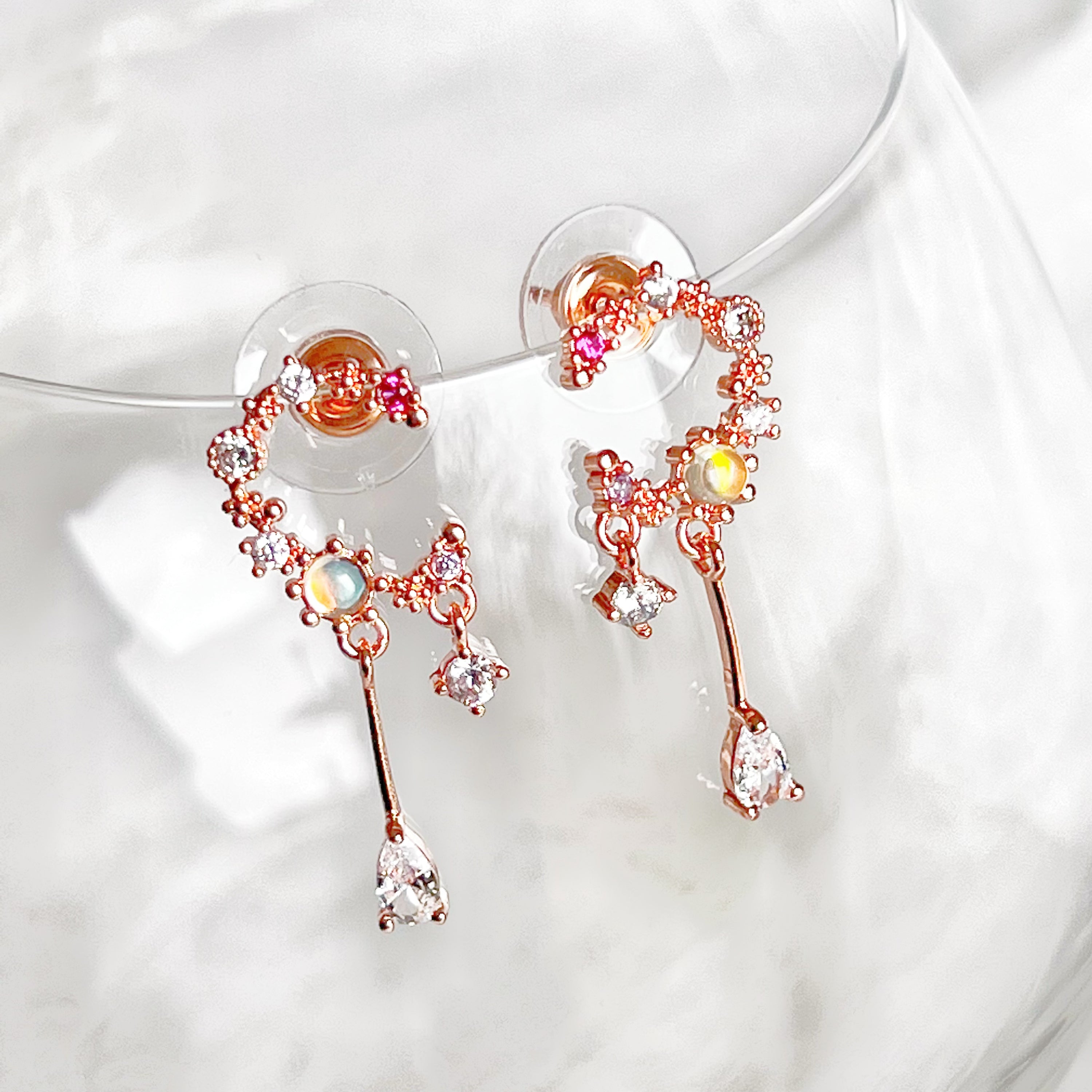 A pair of stunning Rose Gold Moon Drop Earrings featuring a unique wreath design with stars and a crescent moon, crafted from sterling silver and gold-plated bronze.