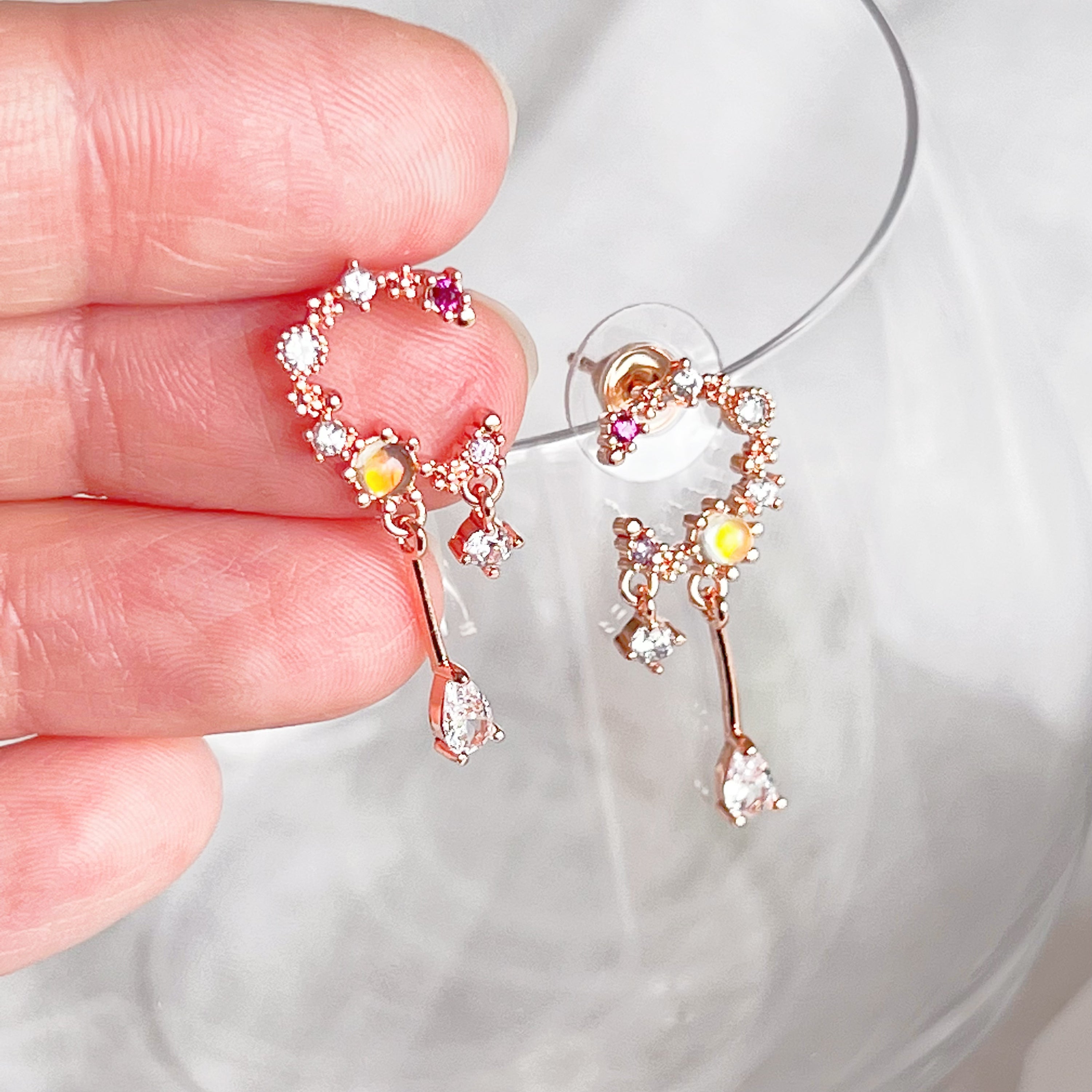 A pair of stunning Rose Gold Moon Drop Earrings featuring a unique wreath design with stars and a crescent moon, crafted from sterling silver and gold-plated bronze.