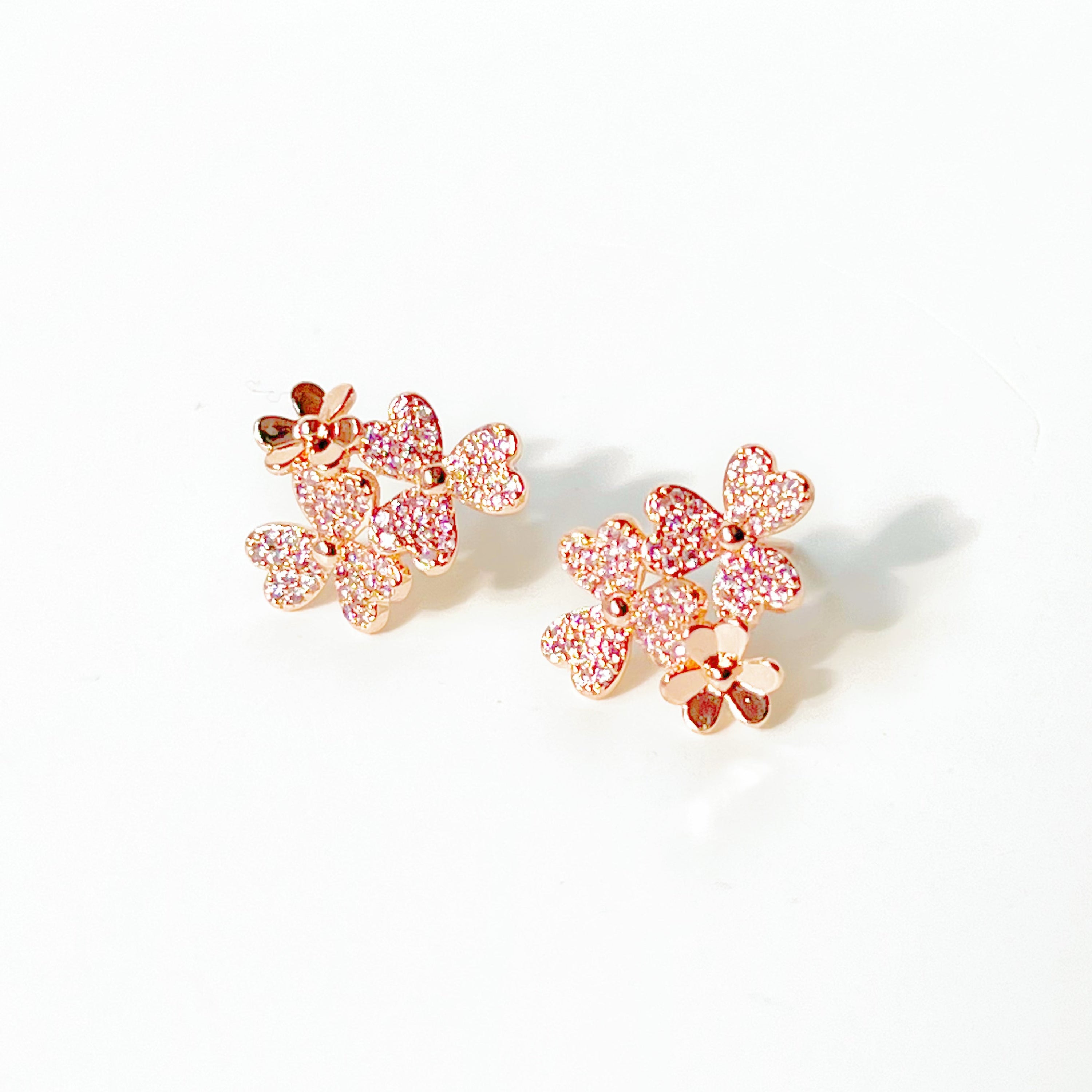 A pair of elegant rose gold shamrock flower earrings with glass crystals, symbolizing good luck.