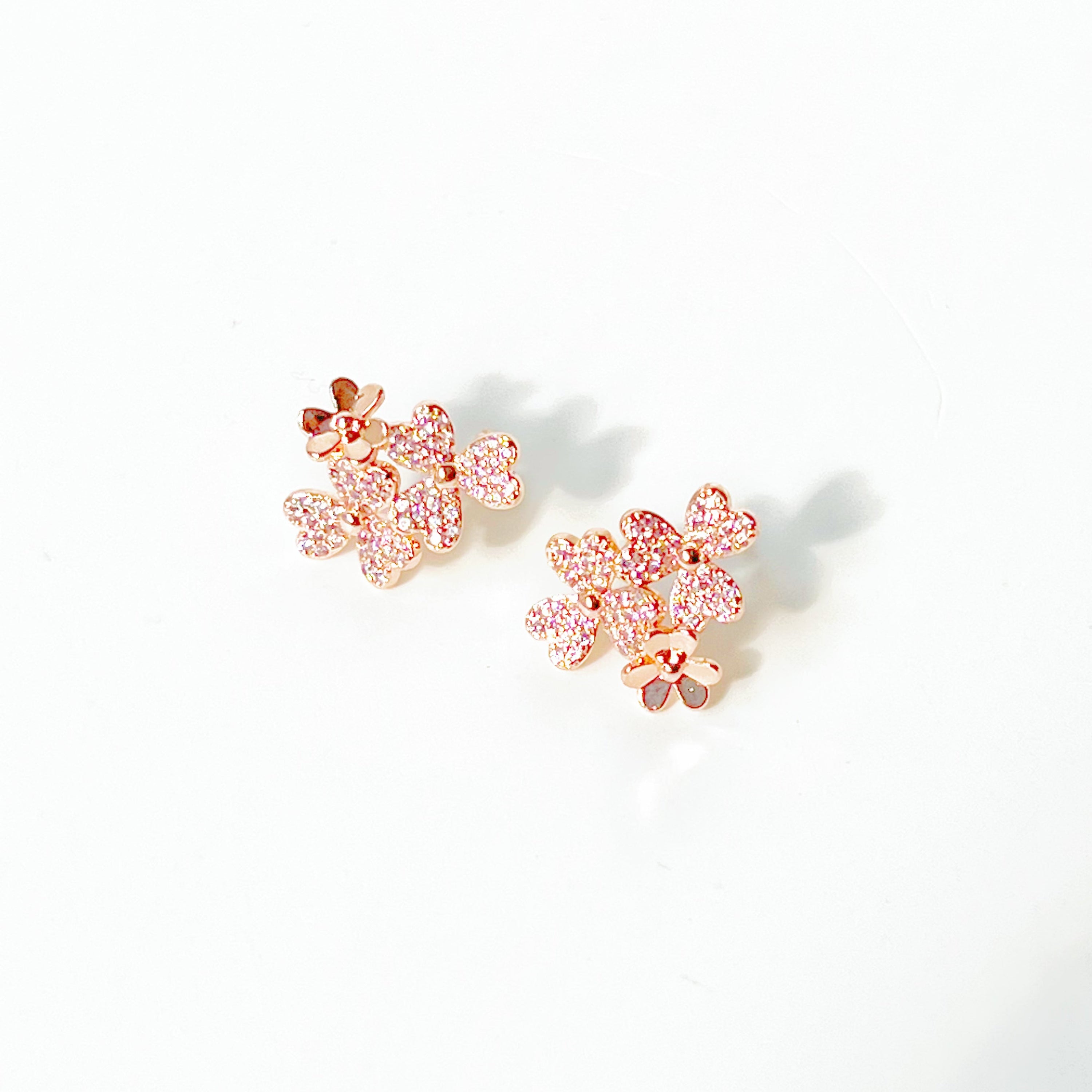 A pair of elegant rose gold shamrock flower earrings with glass crystals, symbolizing good luck.