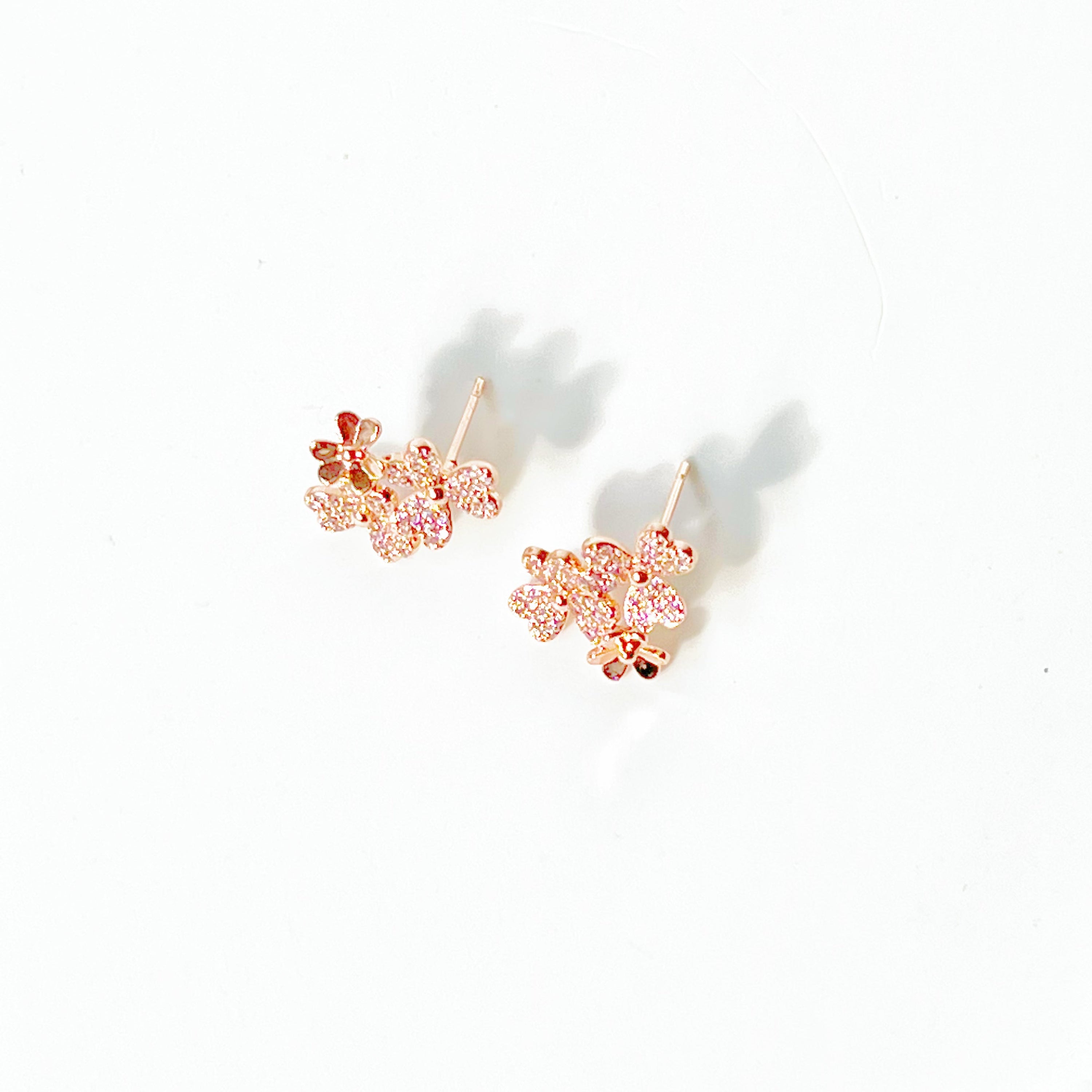 A pair of elegant rose gold shamrock flower earrings with glass crystals, symbolizing good luck.