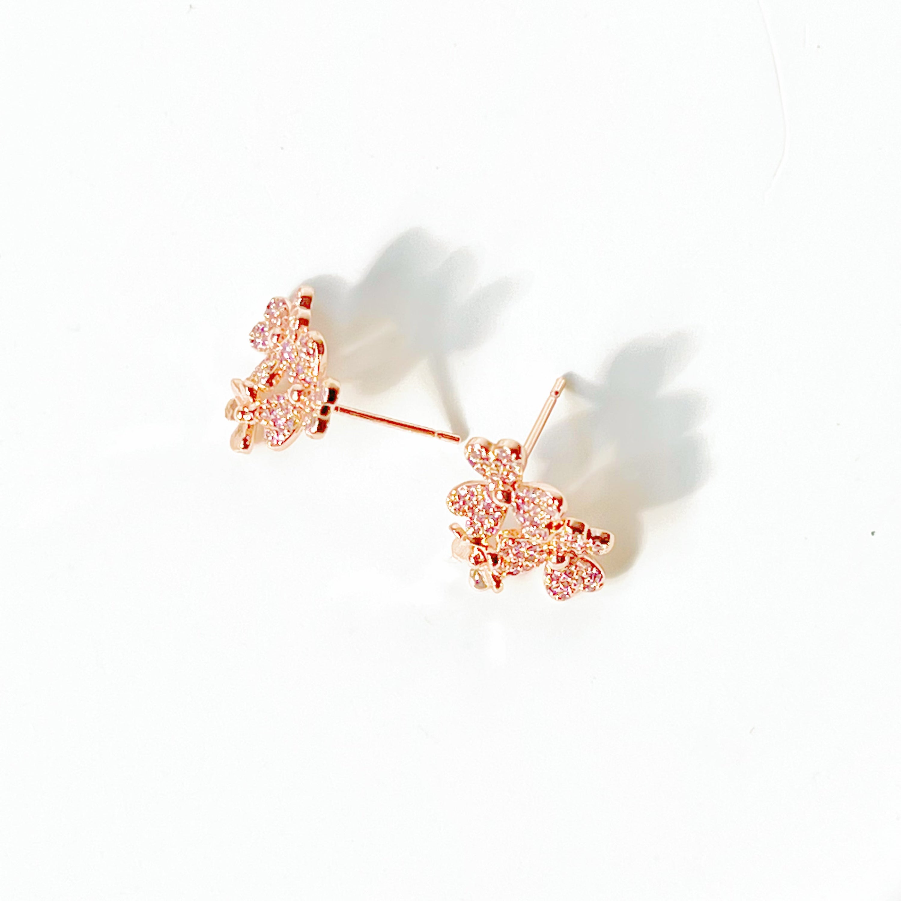 A pair of elegant rose gold shamrock flower earrings with glass crystals, symbolizing good luck.