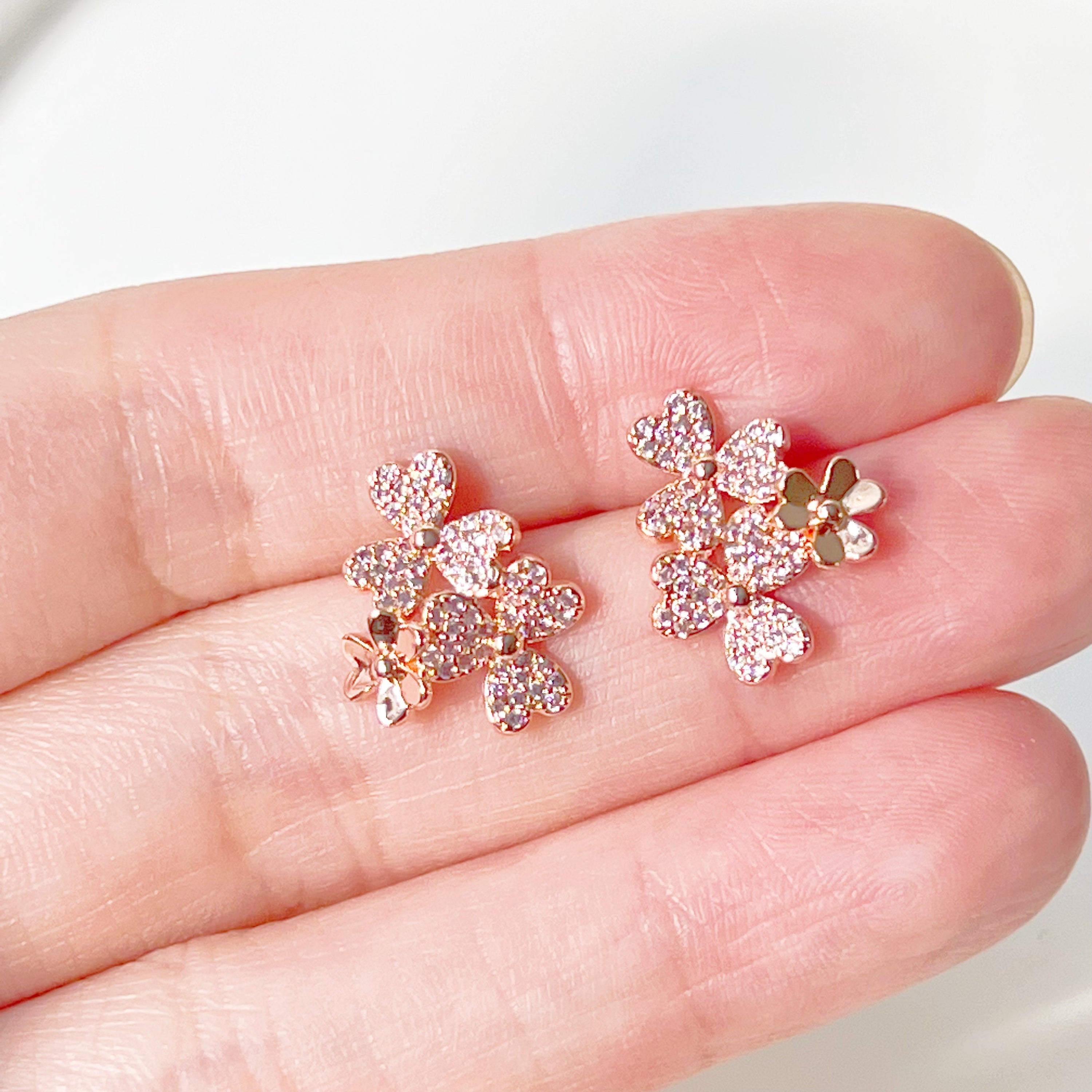 A pair of elegant rose gold shamrock flower earrings with glass crystals, symbolizing good luck.