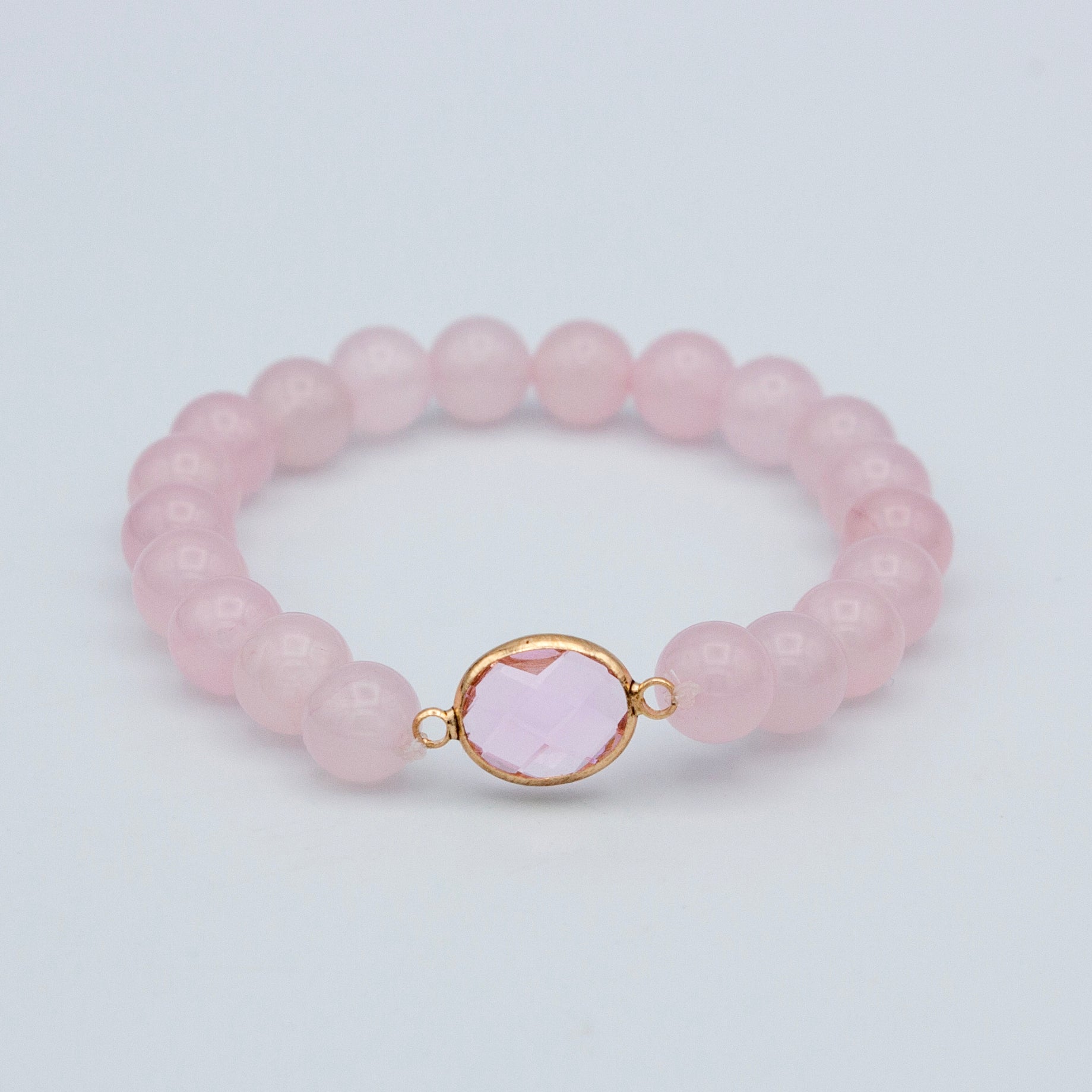 A stylish rose quartz beaded stretch bracelet featuring pink quartz beads and a gold plated brass connector, elegantly displayed.