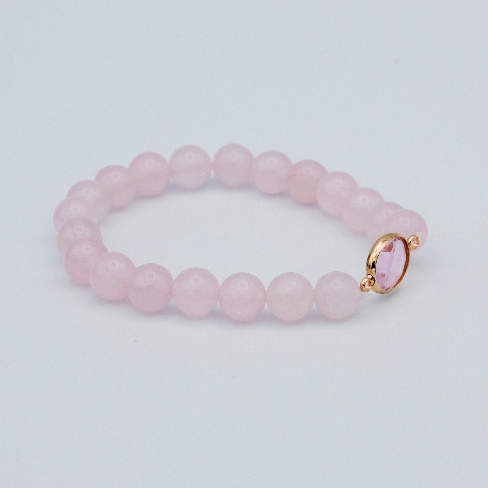 A stylish rose quartz beaded stretch bracelet featuring pink quartz beads and a gold plated brass connector, elegantly displayed.