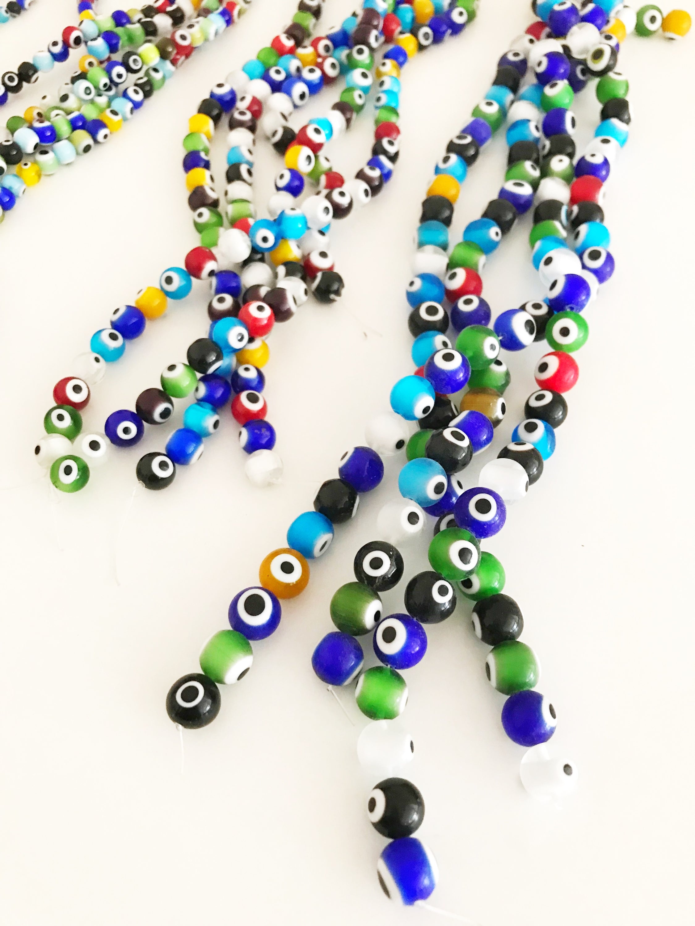 A collection of colorful round evil eye beads in various sizes, showcasing their vibrant colors and glass material, perfect for jewelry making.