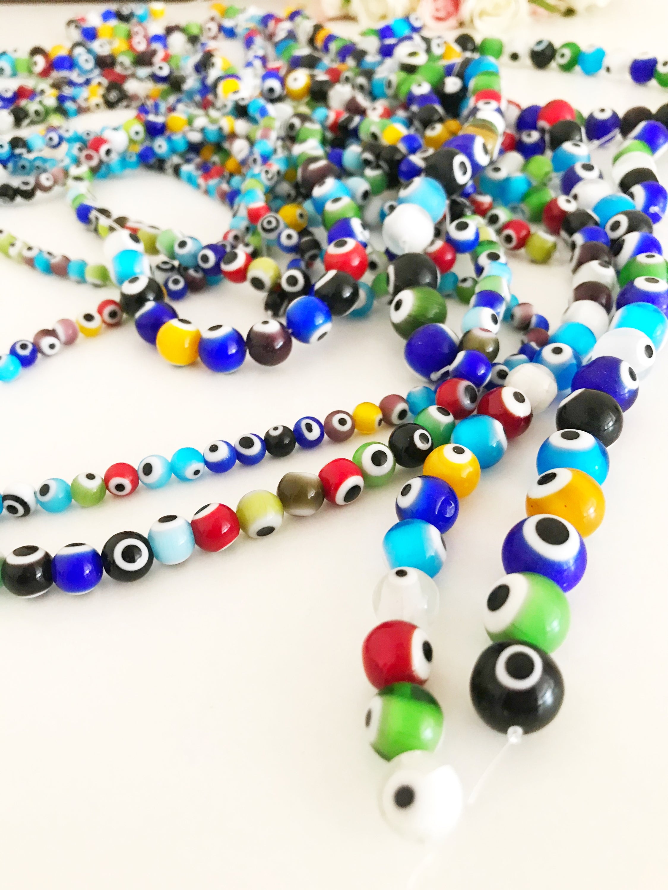 A collection of colorful round evil eye beads in various sizes, showcasing their vibrant colors and glass material, perfect for jewelry making.