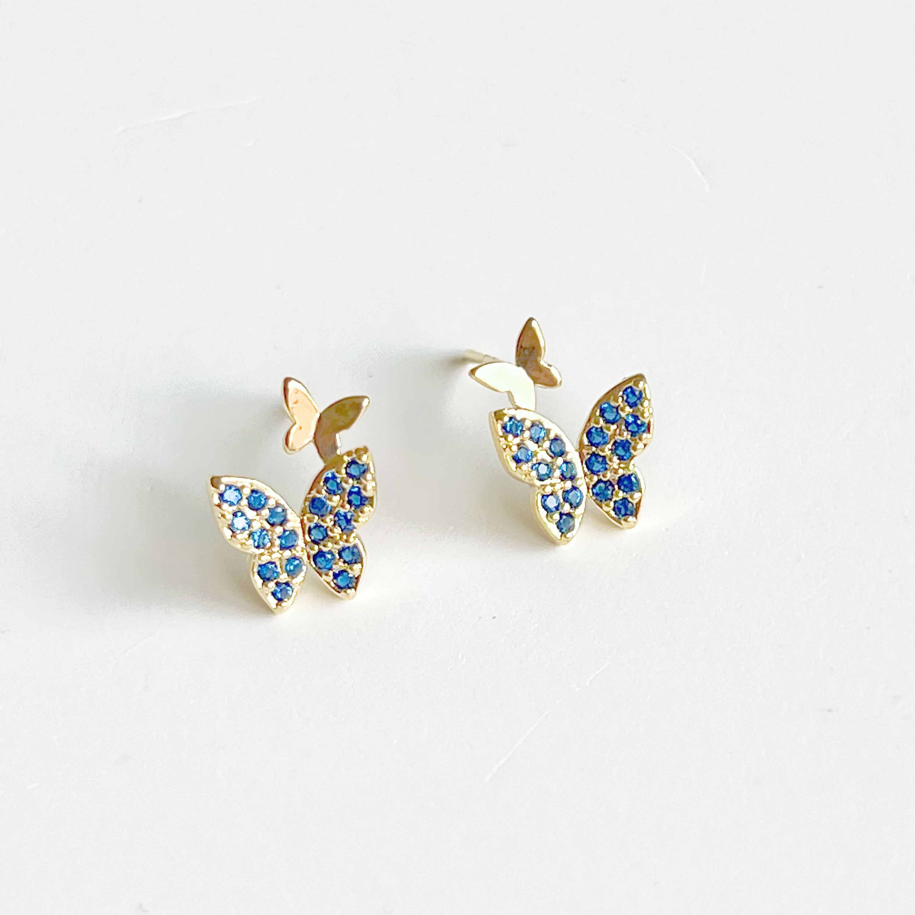 A pair of royal blue crystal butterfly earrings made from gold-plated sterling silver and bronze, showcasing intricate design and shimmering blue zircon.