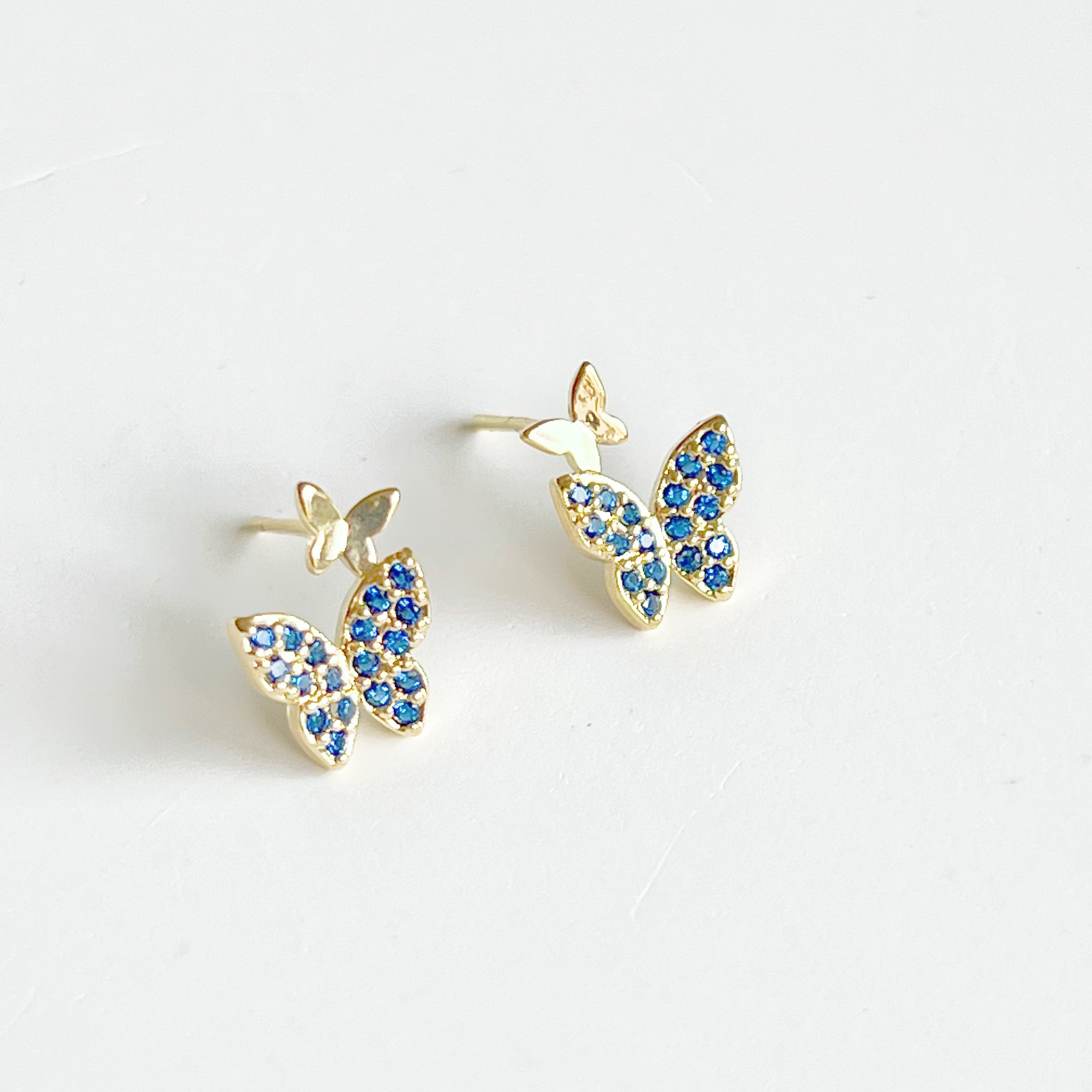 A pair of royal blue crystal butterfly earrings made from gold-plated sterling silver and bronze, showcasing intricate design and shimmering blue zircon.