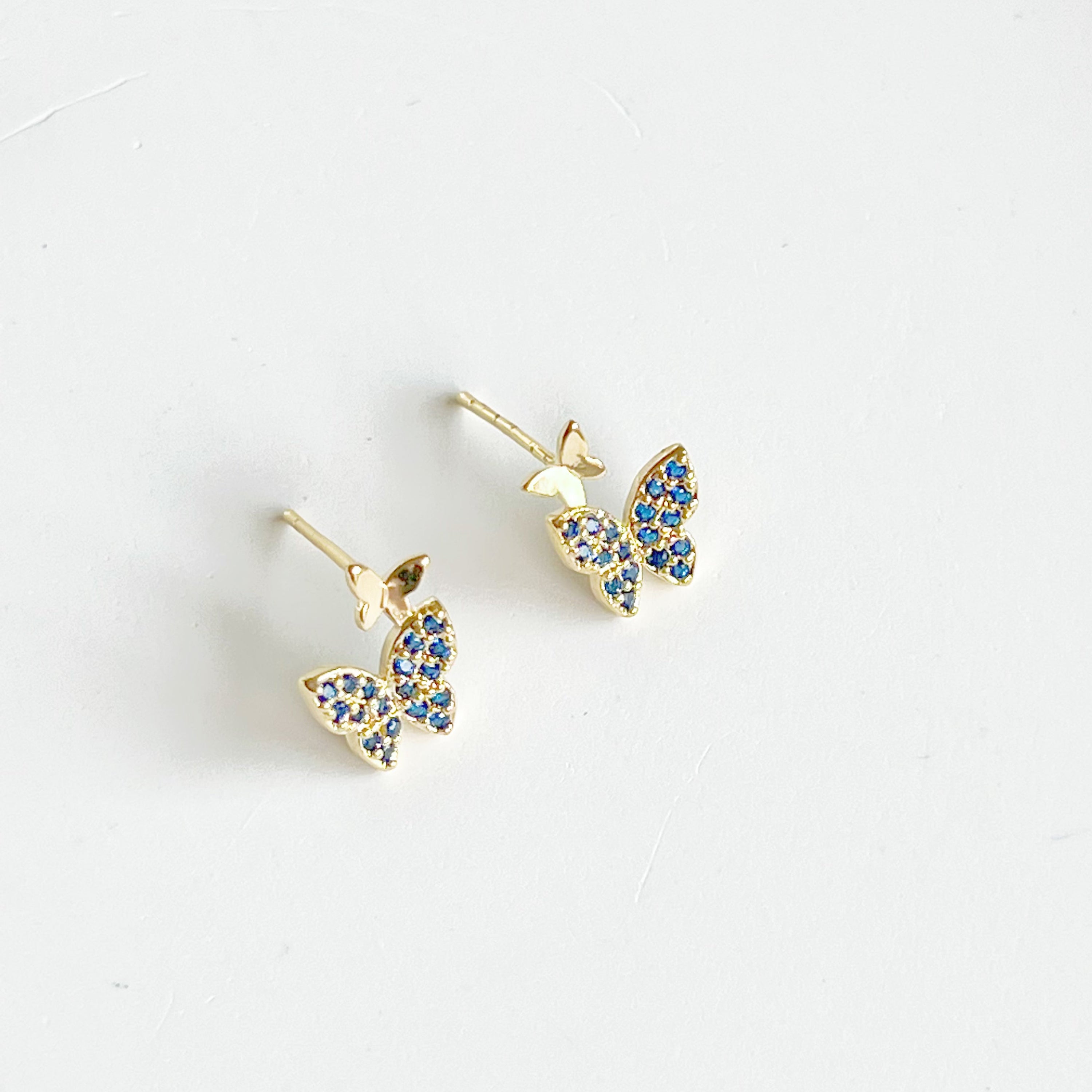 A pair of royal blue crystal butterfly earrings made from gold-plated sterling silver and bronze, showcasing intricate design and shimmering blue zircon.