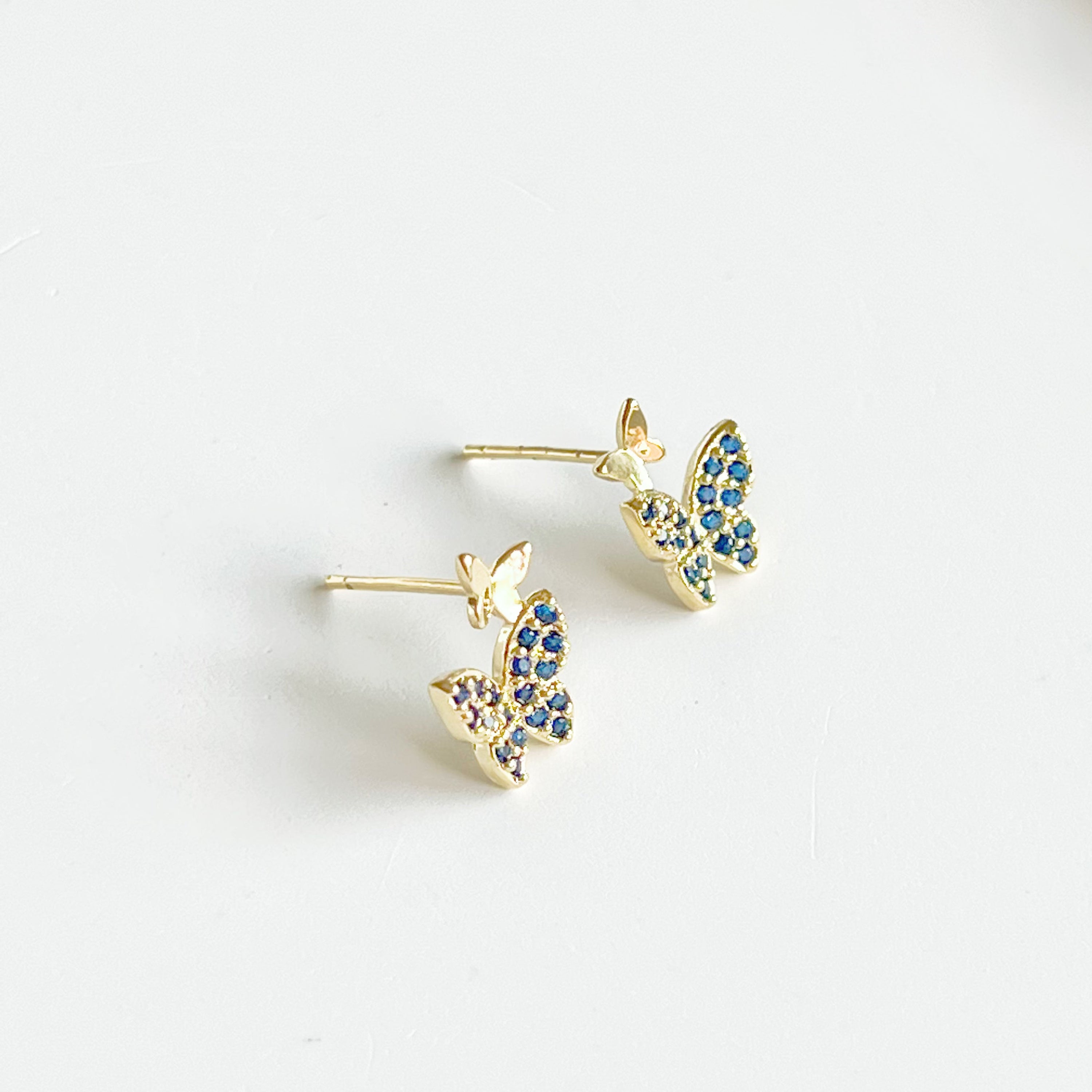 A pair of royal blue crystal butterfly earrings made from gold-plated sterling silver and bronze, showcasing intricate design and shimmering blue zircon.