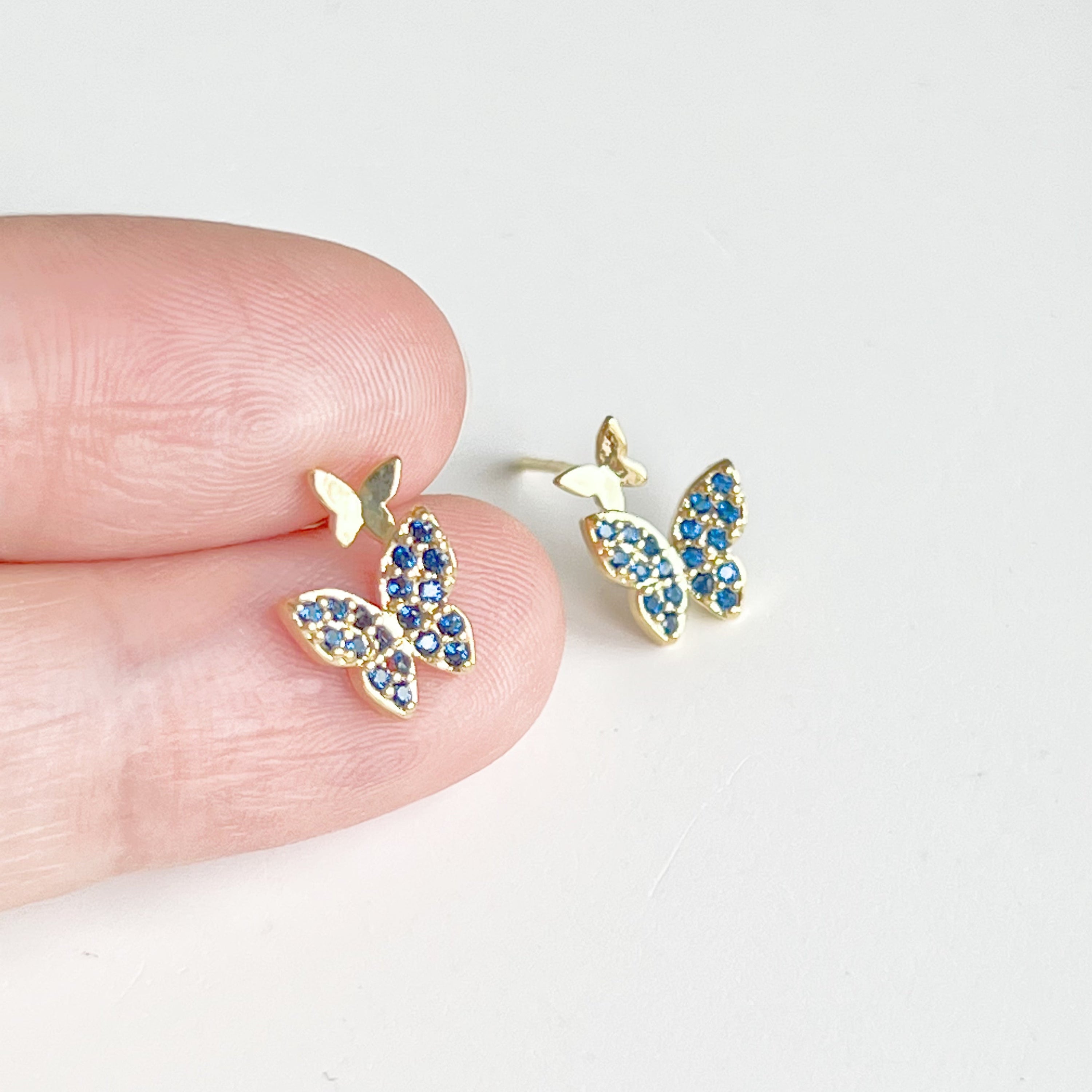 A pair of royal blue crystal butterfly earrings made from gold-plated sterling silver and bronze, showcasing intricate design and shimmering blue zircon.