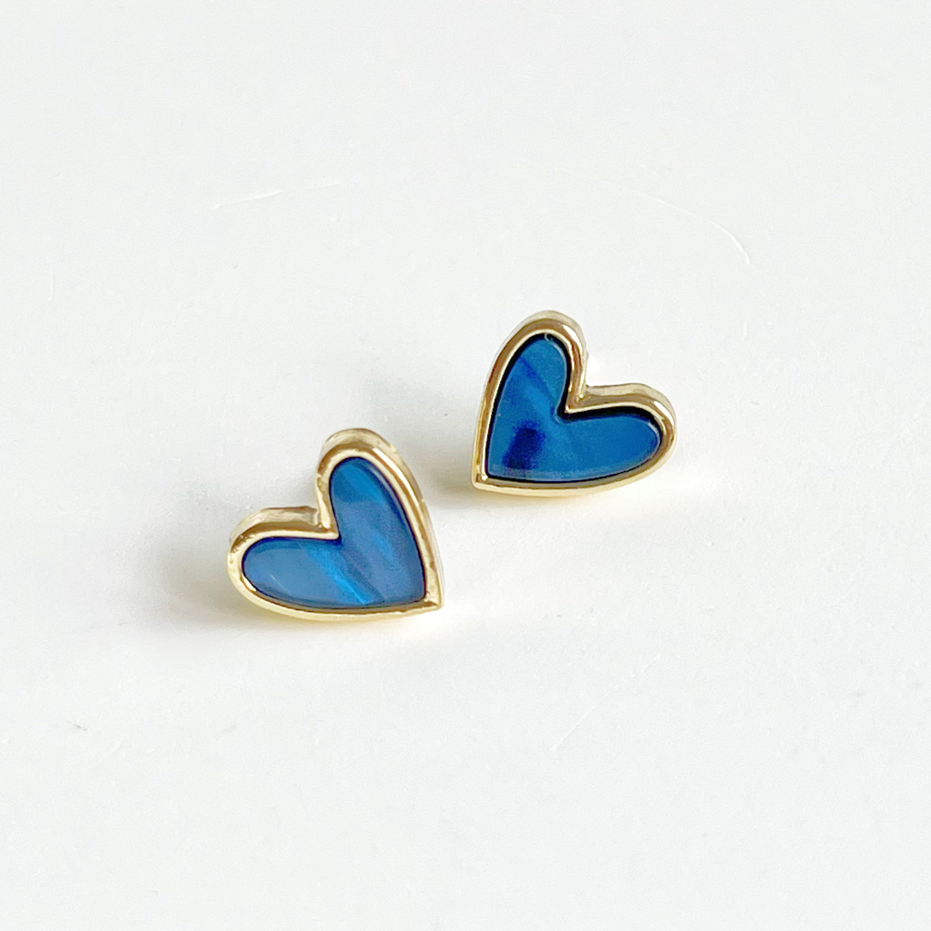 A pair of royal blue heart stud earrings with a gold color base, elegantly displayed in a gift box.