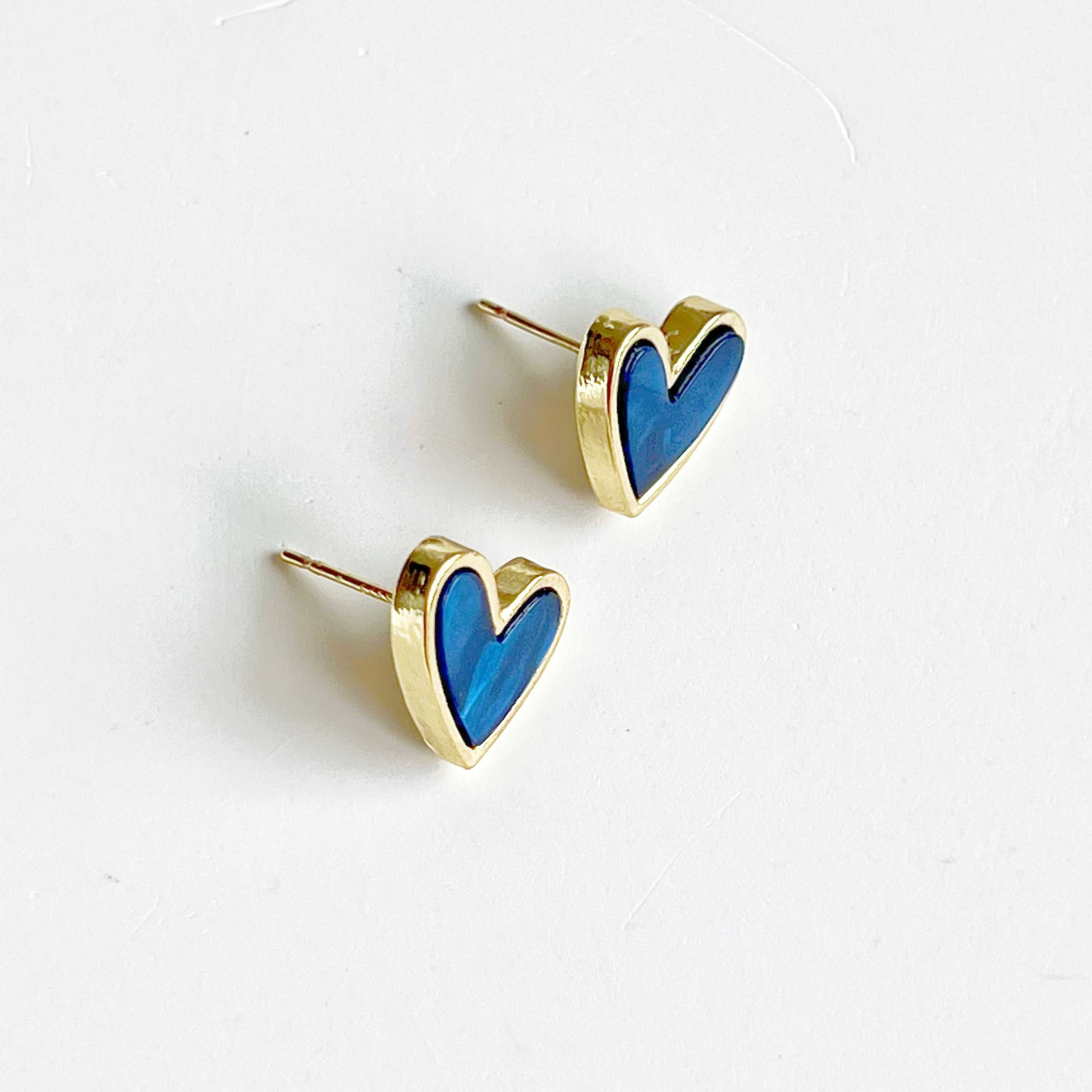 A pair of royal blue heart stud earrings with a gold color base, elegantly displayed in a gift box.