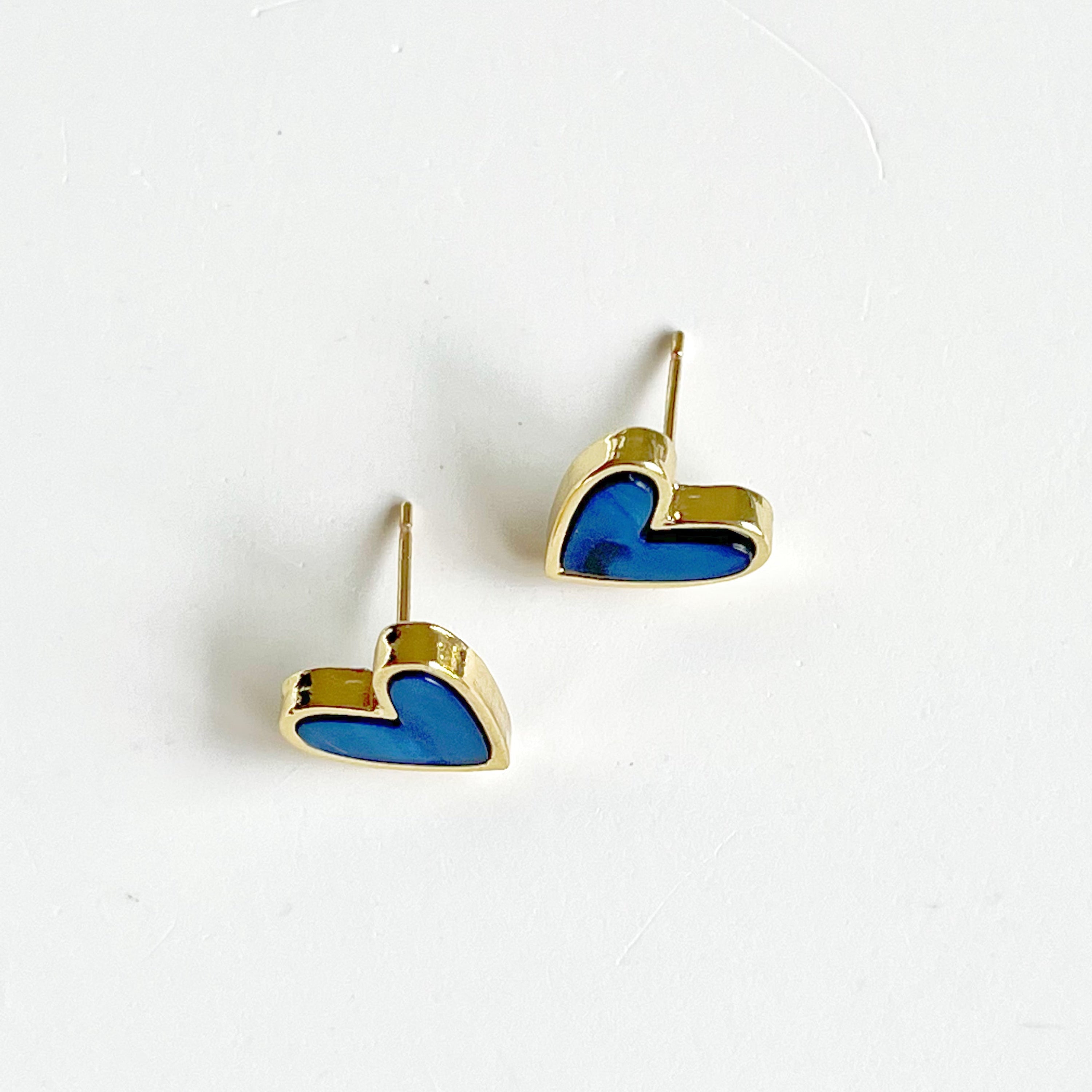 A pair of royal blue heart stud earrings with a gold color base, elegantly displayed in a gift box.