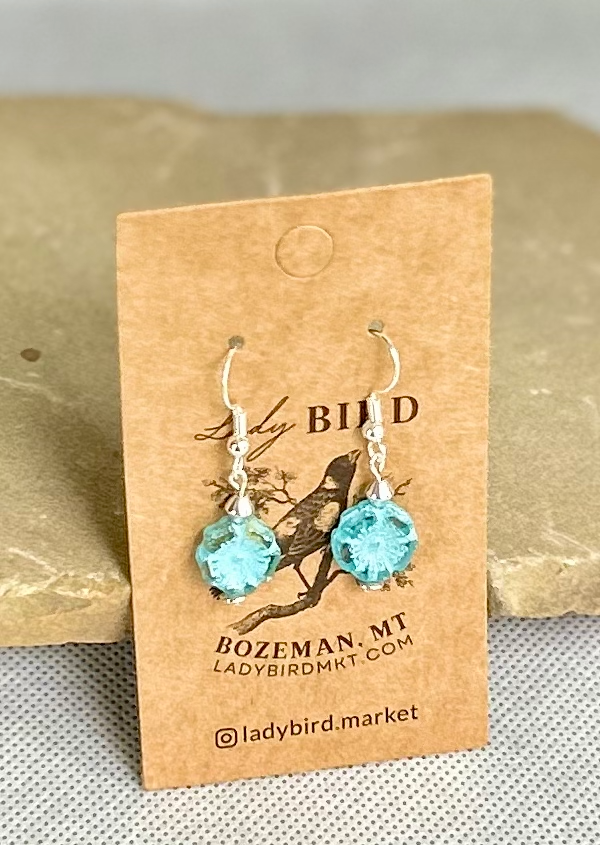 Rustic light blue etched hibiscus flower earrings made from Czech glass, featuring a wild rose design.