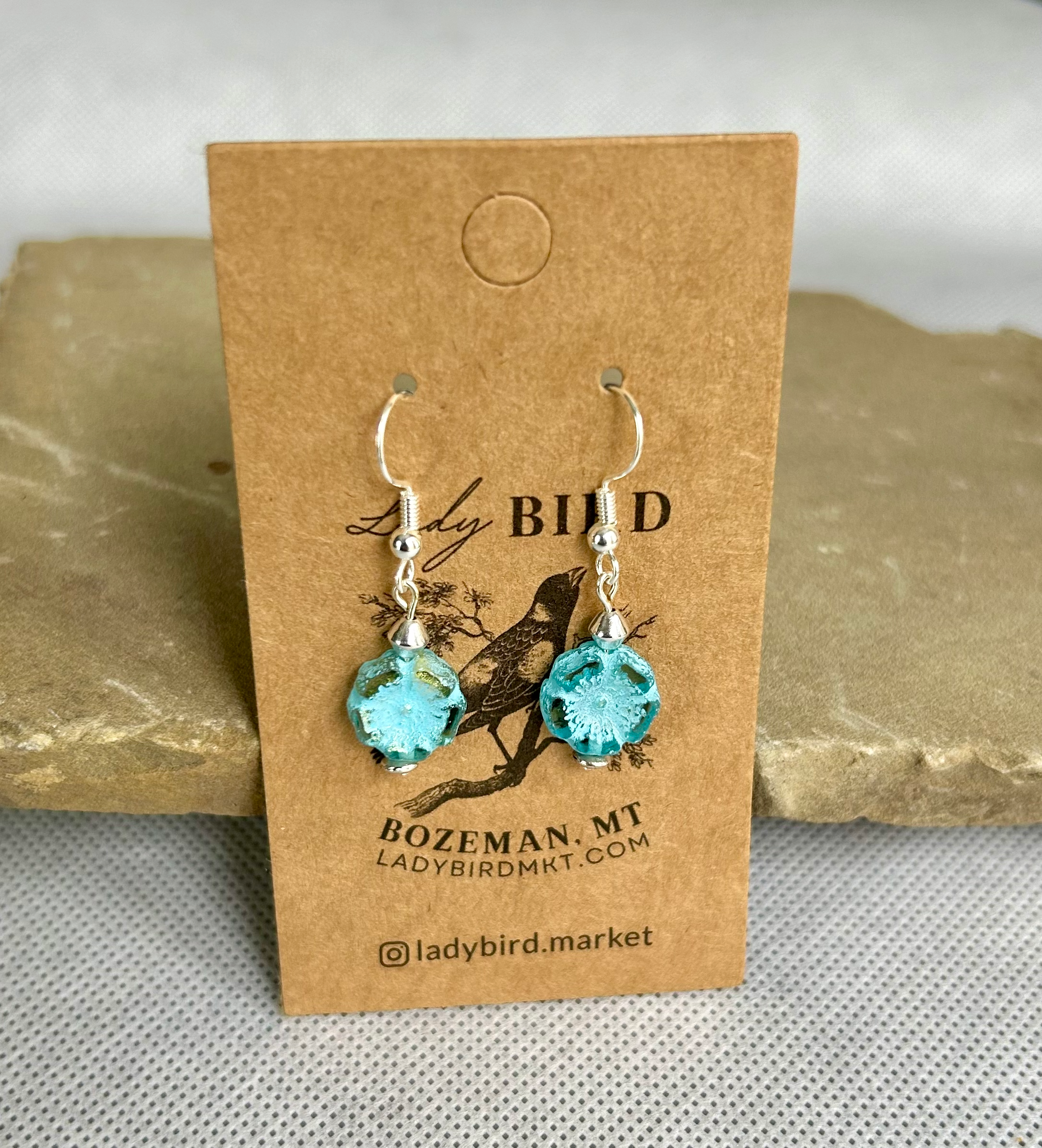 Rustic light blue etched hibiscus flower earrings made from Czech glass, featuring a wild rose design.