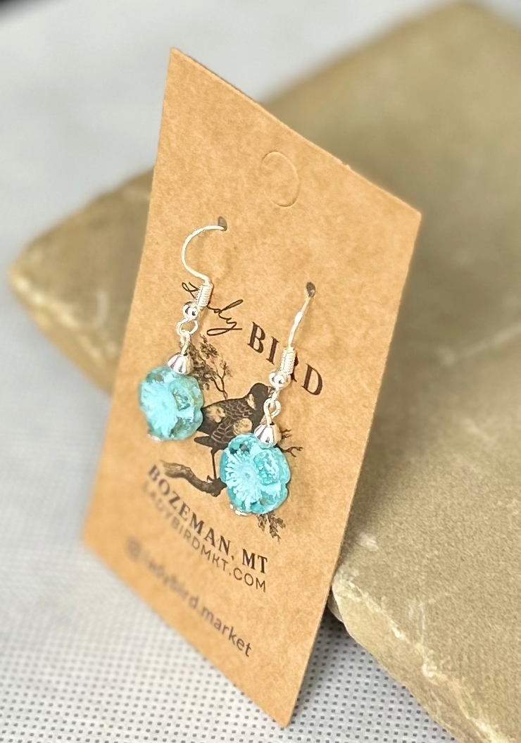 Rustic light blue etched hibiscus flower earrings made from Czech glass, featuring a wild rose design.