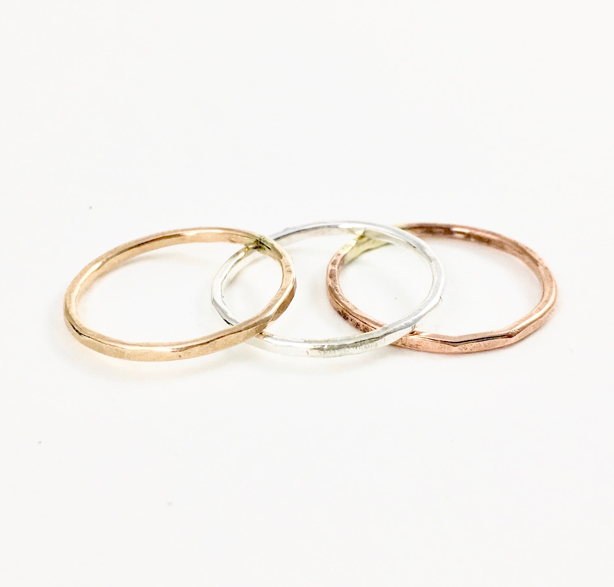 A set of Rustic Stacking Rings featuring a textured hammered finish, made from recycled metals in gold, rose gold, and silver.