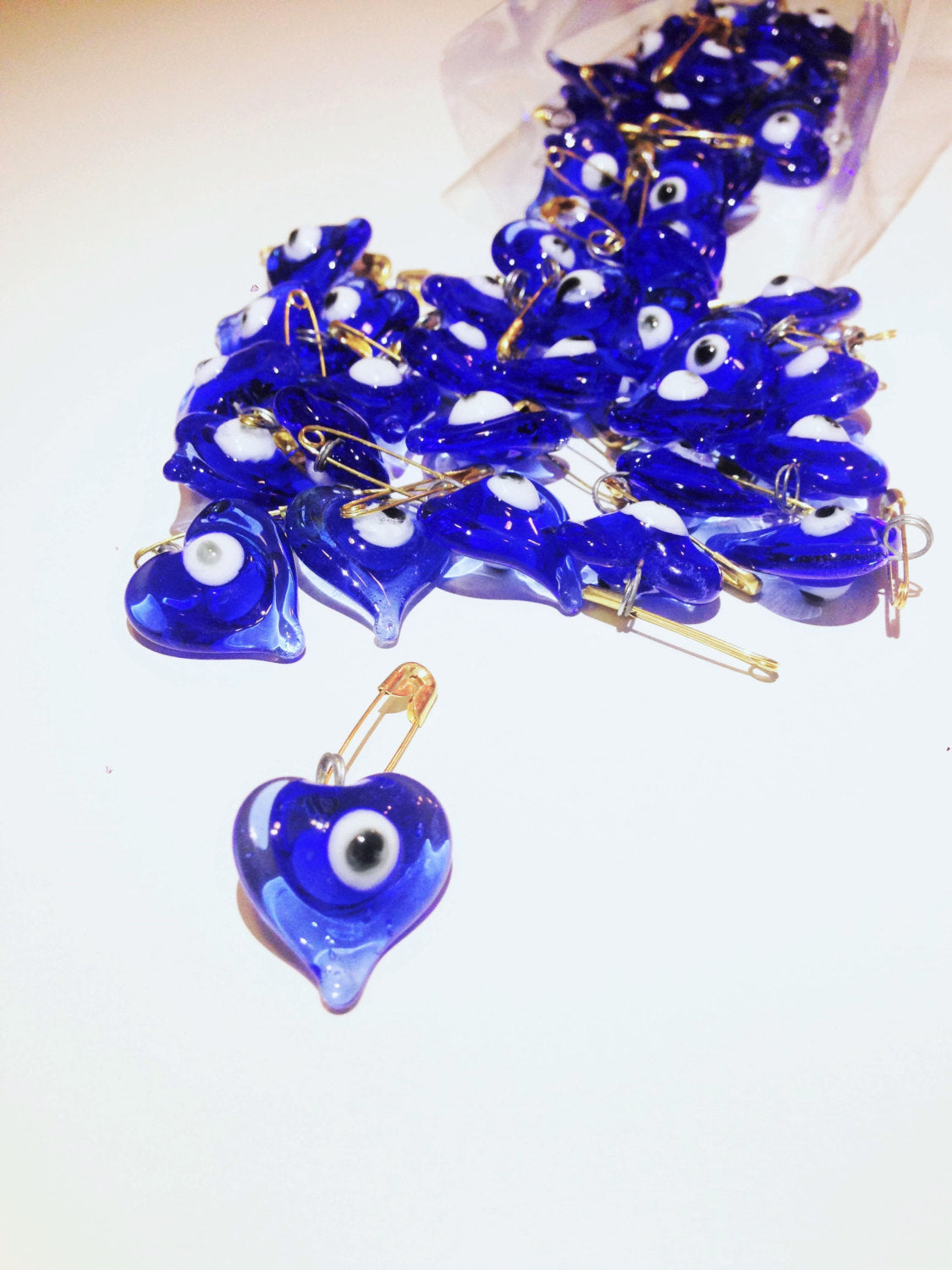 A collection of 50 heart-shaped glass evil eye safety pins, symbolizing protection and luck, perfect for weddings and special events.