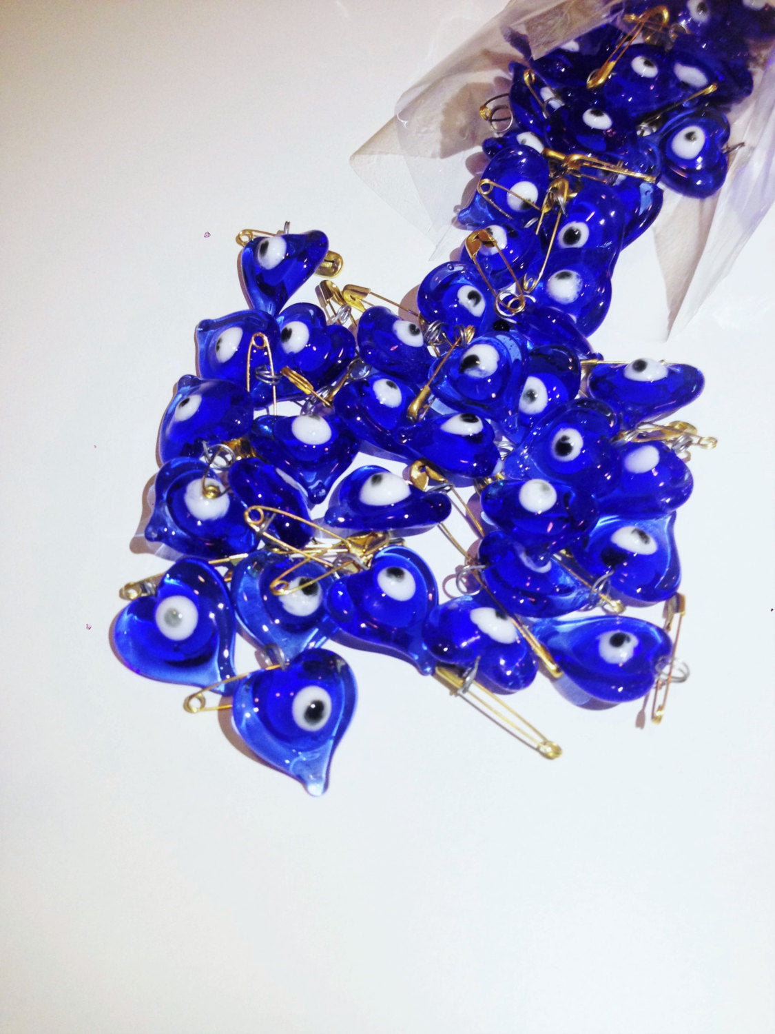 A collection of 50 heart-shaped glass evil eye safety pins, symbolizing protection and luck, perfect for weddings and special events.