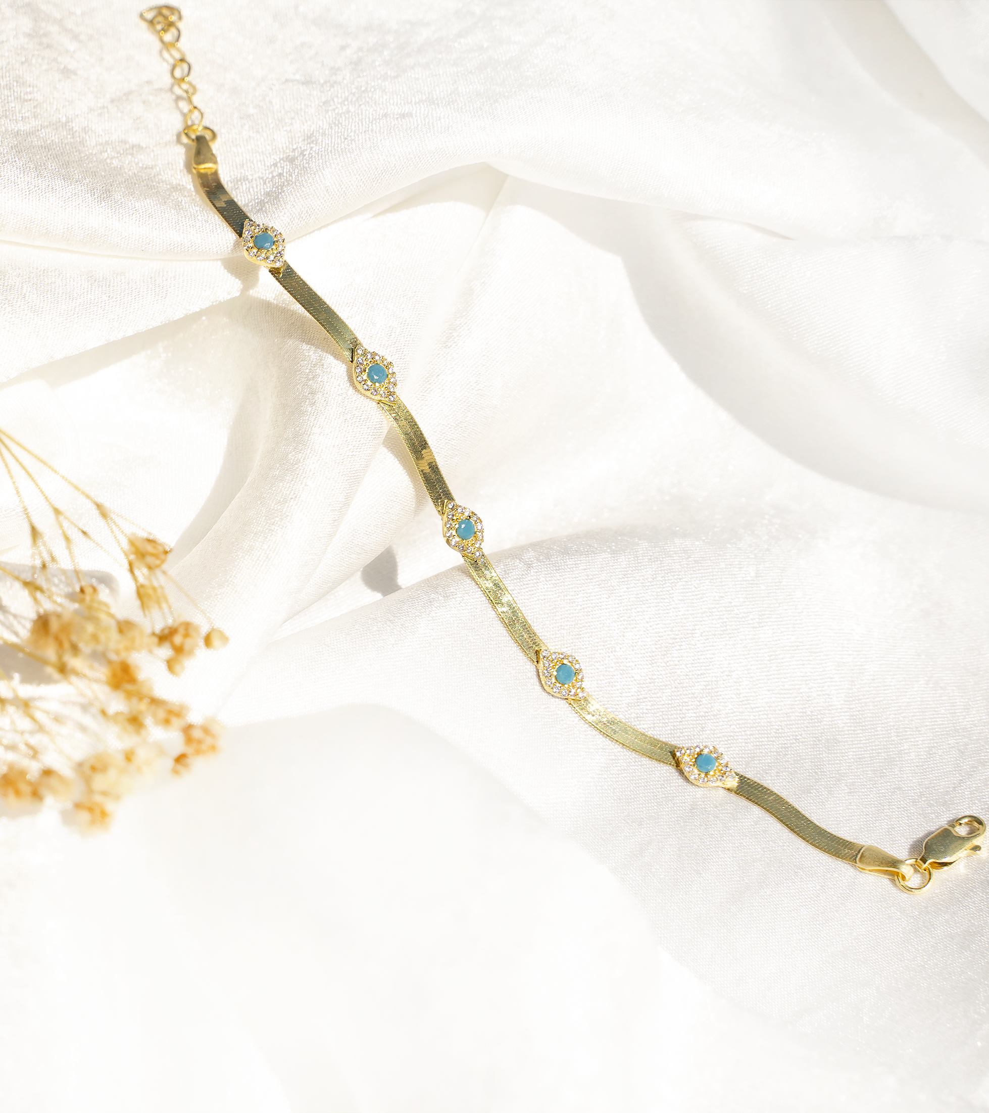 SAMIRA Bracelet featuring herringbone design with evil eye charms, cubic zirconias, and turquoise accents, set in yellow gold plated 925 sterling silver.