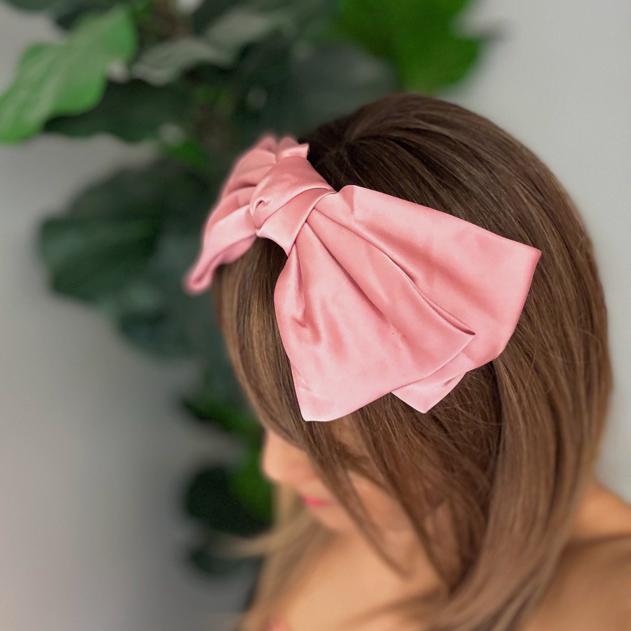 A stylish Satin Bow Crown Headband featuring a large doubled satin bow on a slim body, perfect for enhancing any outfit.