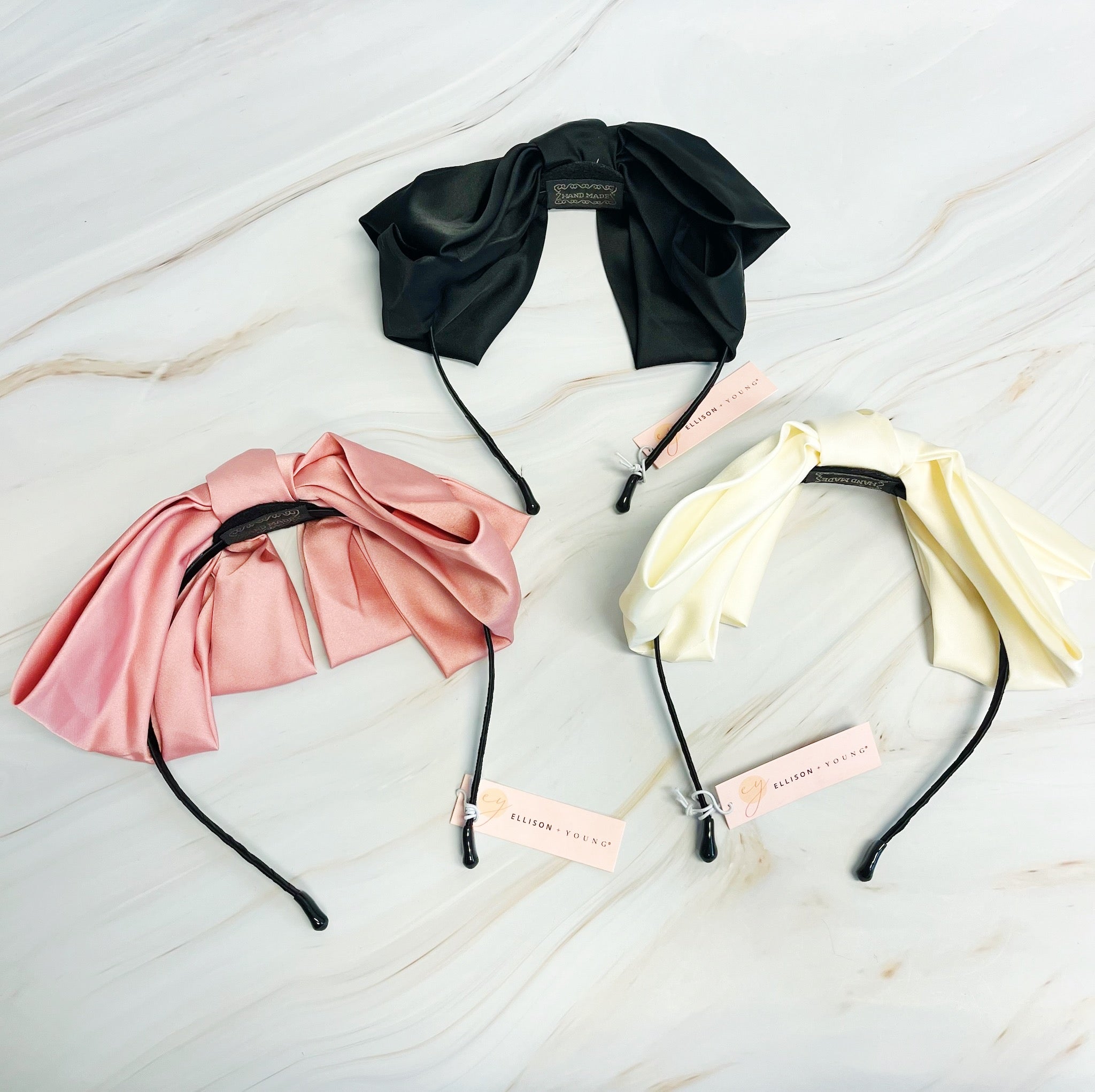 A stylish Satin Bow Crown Headband featuring a large doubled satin bow on a slim body, perfect for enhancing any outfit.