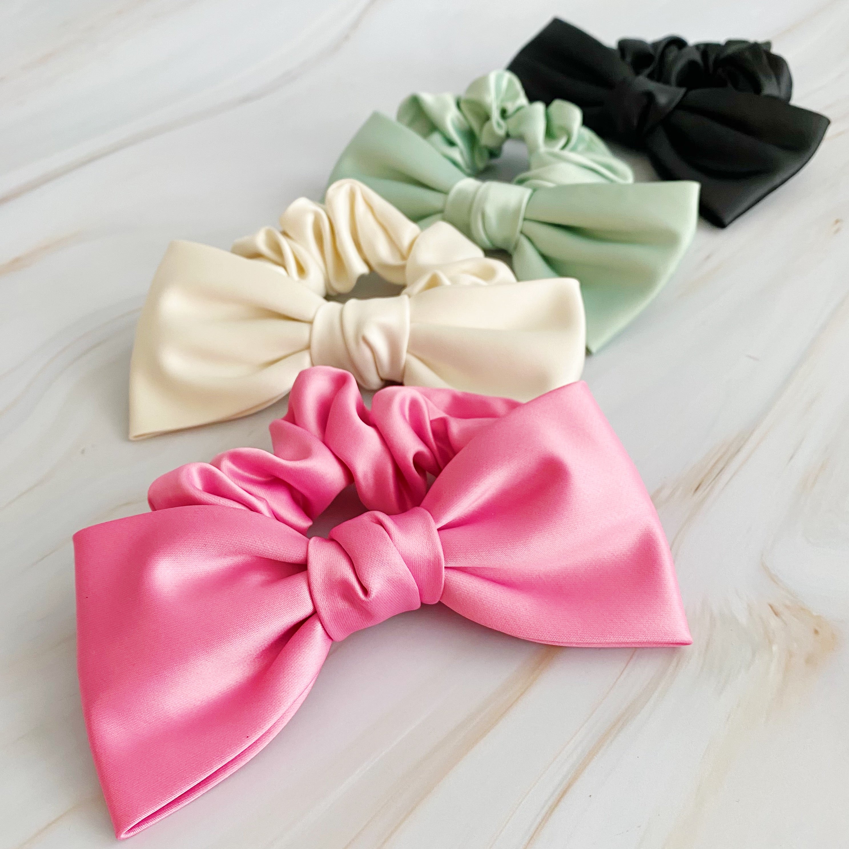 A stylish satin bow tie hair scrunchie in elegant colors, perfect for adding sophistication to any hairstyle.