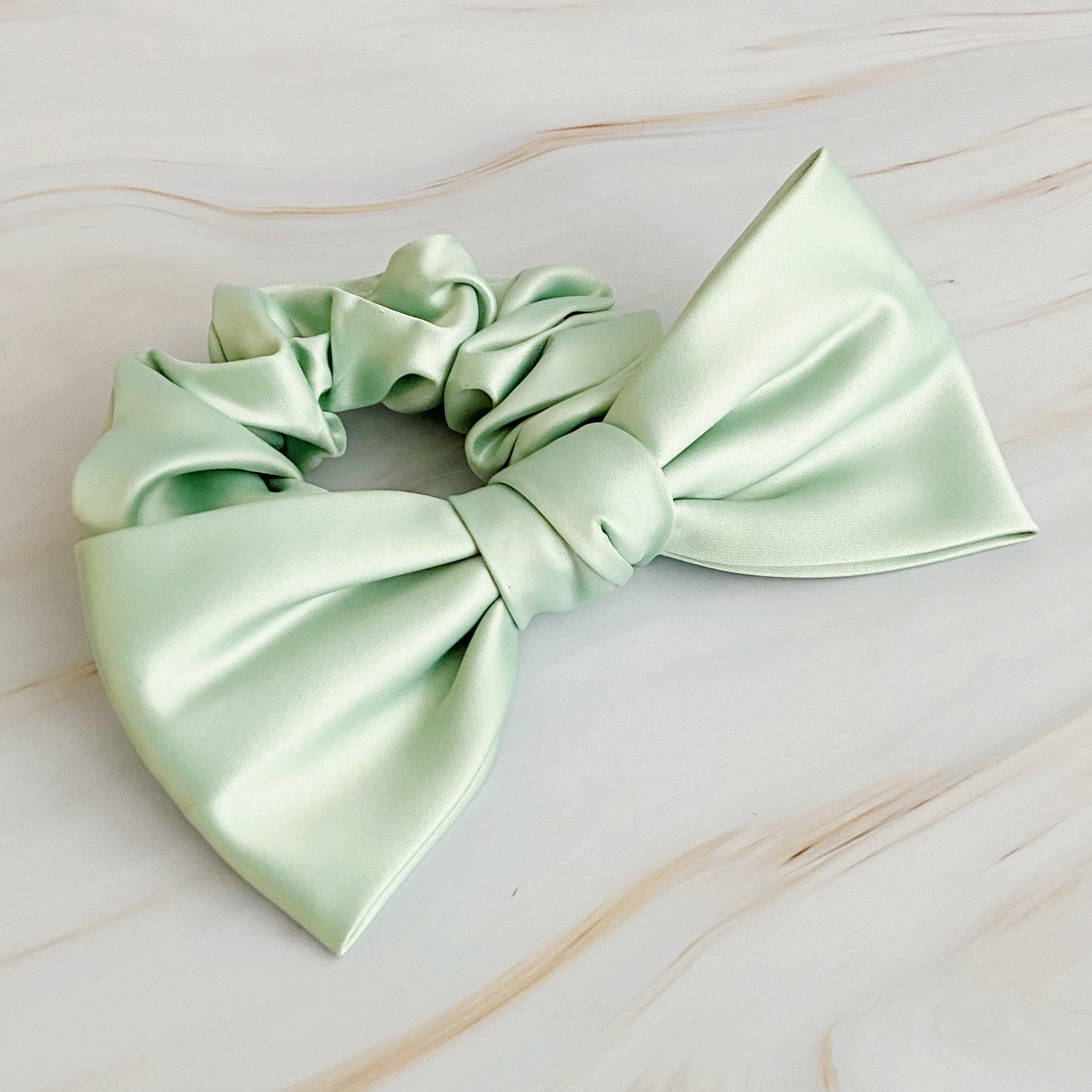 A stylish satin bow tie hair scrunchie in elegant colors, perfect for adding sophistication to any hairstyle.