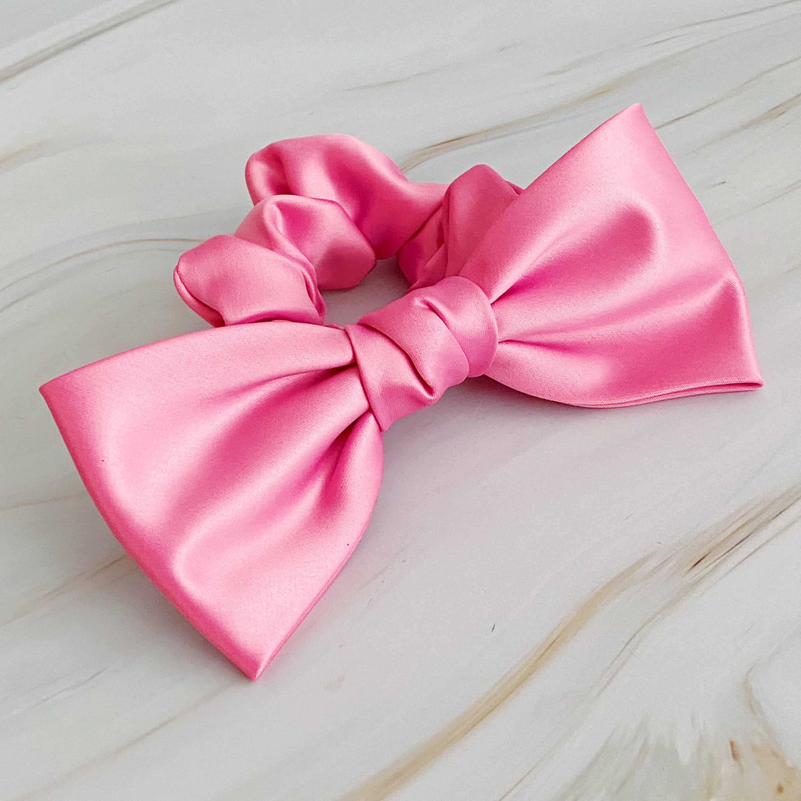 A stylish satin bow tie hair scrunchie in elegant colors, perfect for adding sophistication to any hairstyle.