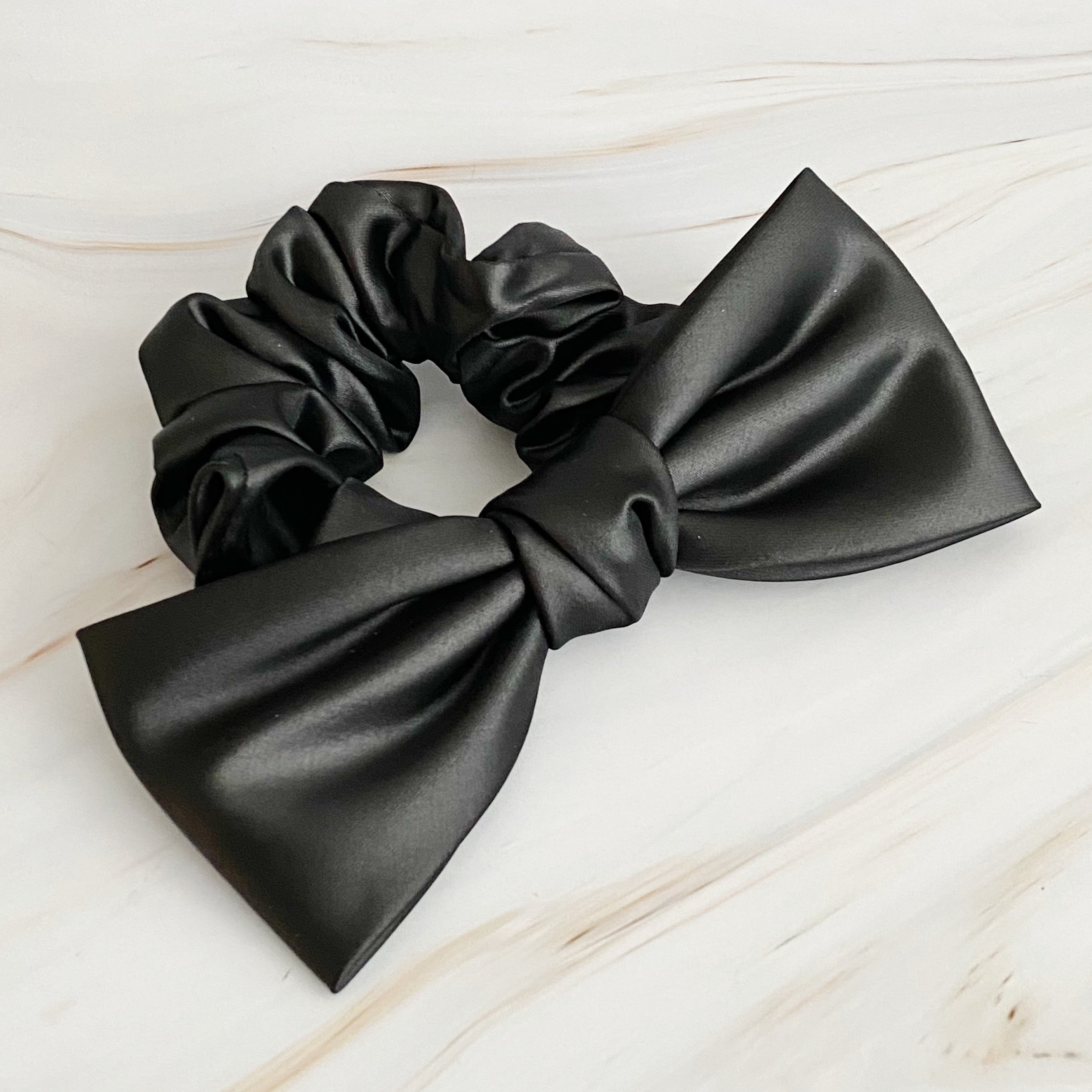 A stylish satin bow tie hair scrunchie in elegant colors, perfect for adding sophistication to any hairstyle.