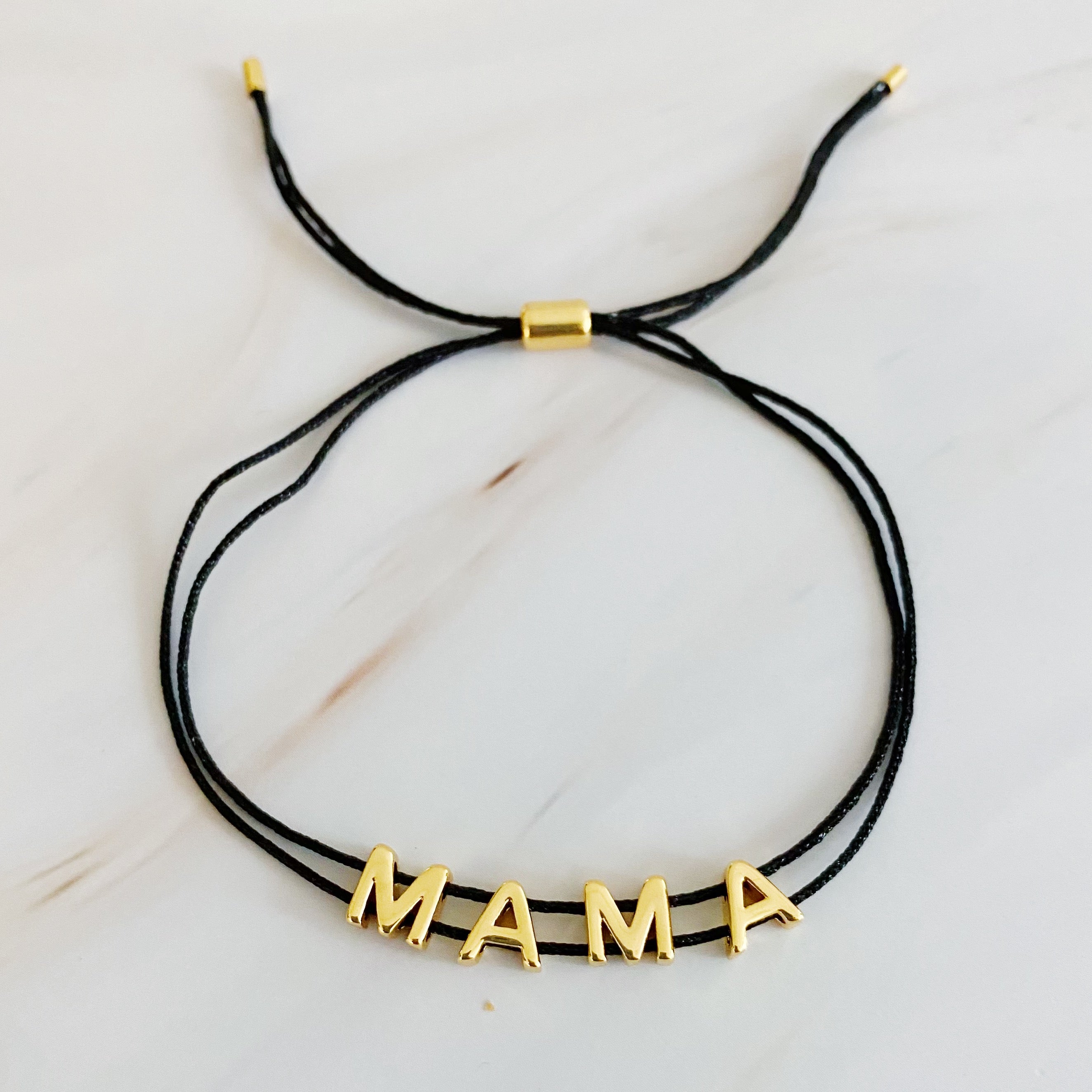 A stylish Satin Thread Mama Bracelet featuring a slim satin thread with golden 'MAMA' lettering, adjustable for a perfect fit.