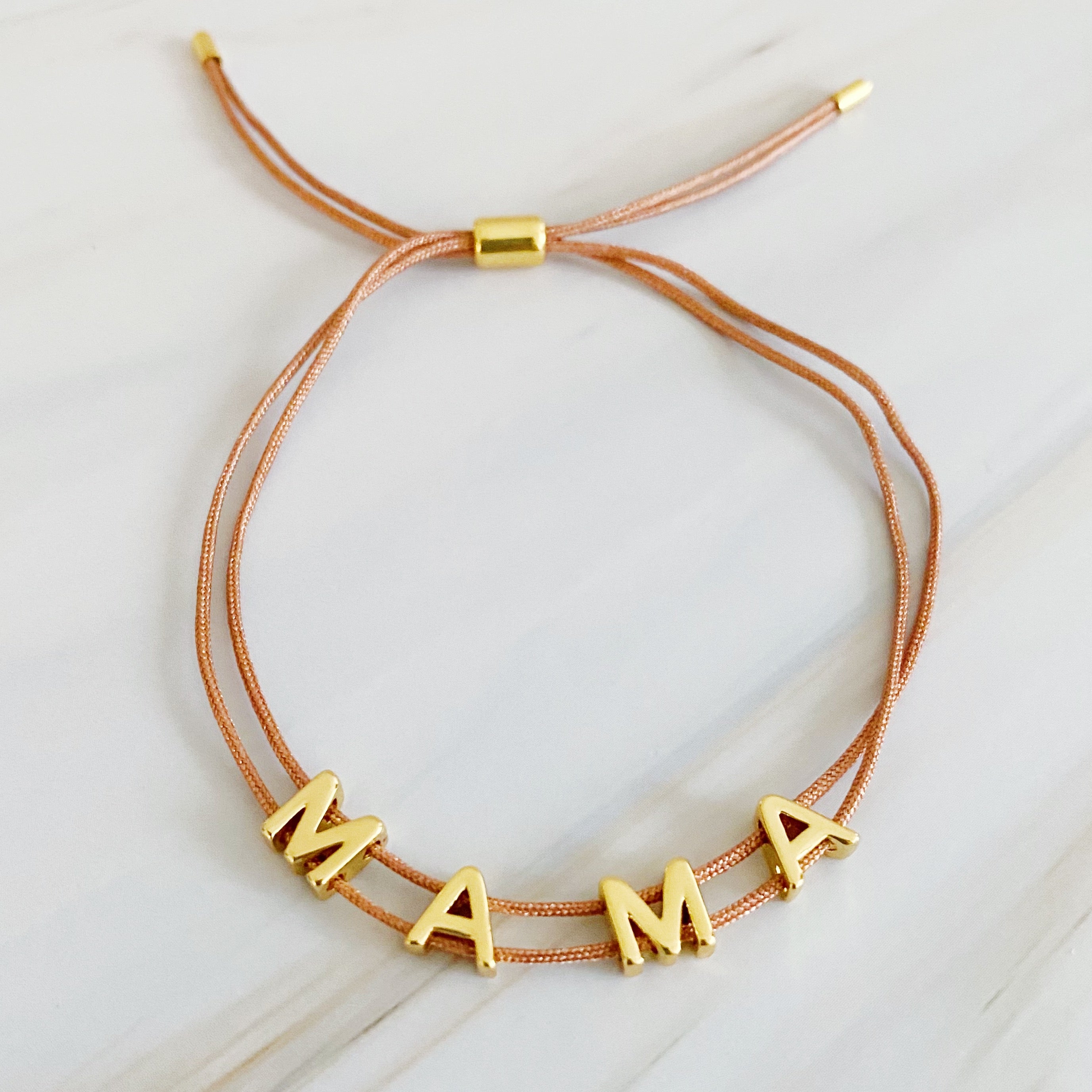 A stylish Satin Thread Mama Bracelet featuring a slim satin thread with golden 'MAMA' lettering, adjustable for a perfect fit.