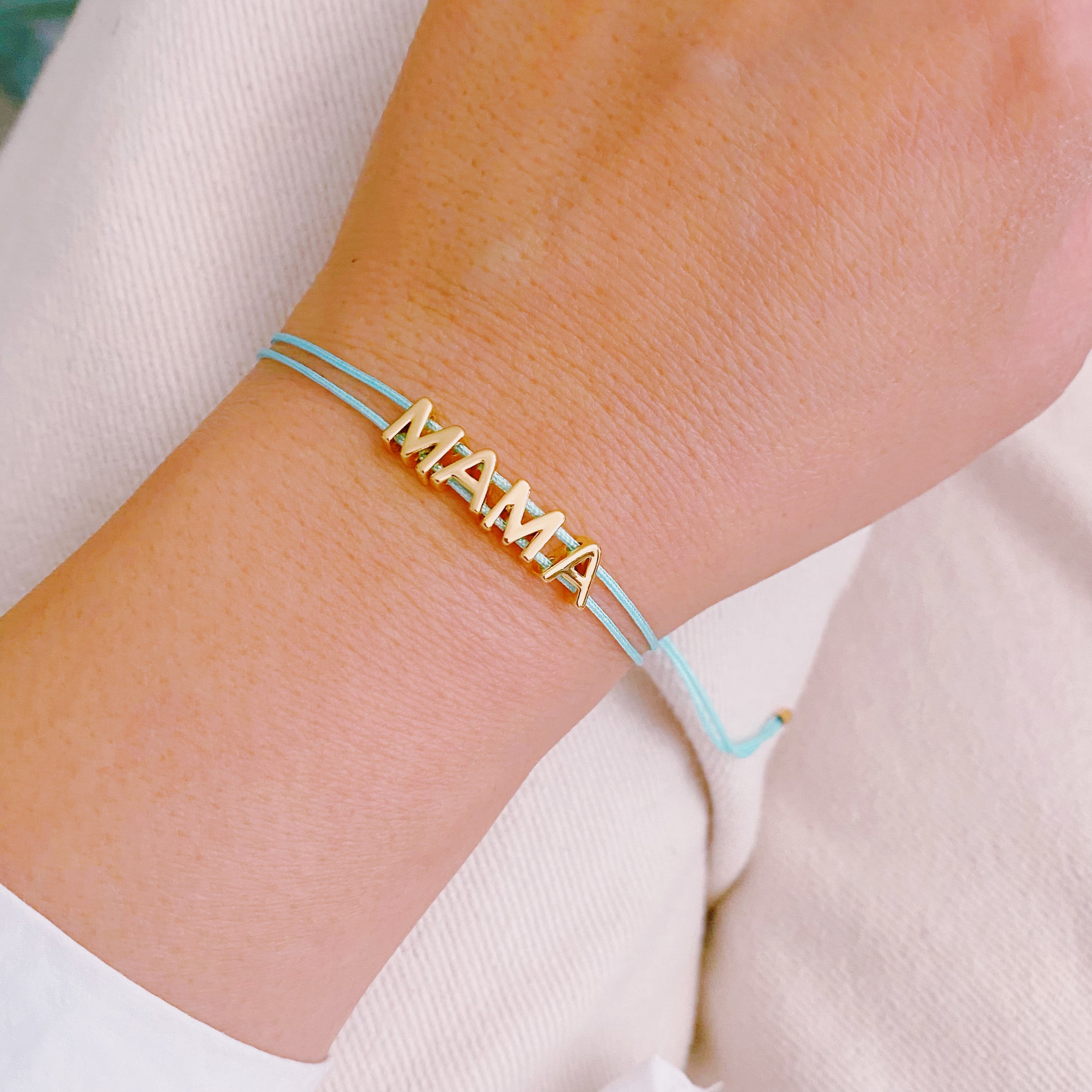 A stylish Satin Thread Mama Bracelet featuring a slim satin thread with golden 'MAMA' lettering, adjustable for a perfect fit.