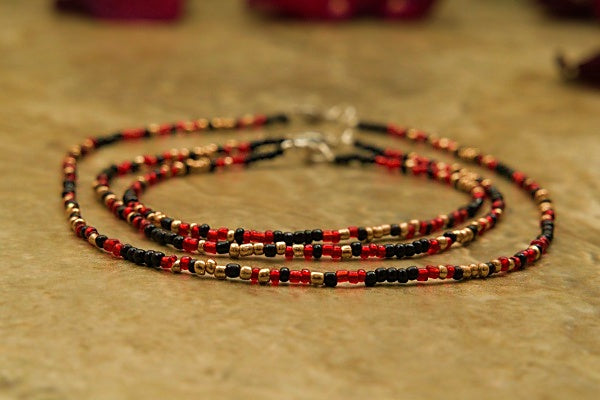 Handcrafted seed bead bracelet featuring the word 'focus' in morse code with red, gold, and black beads.