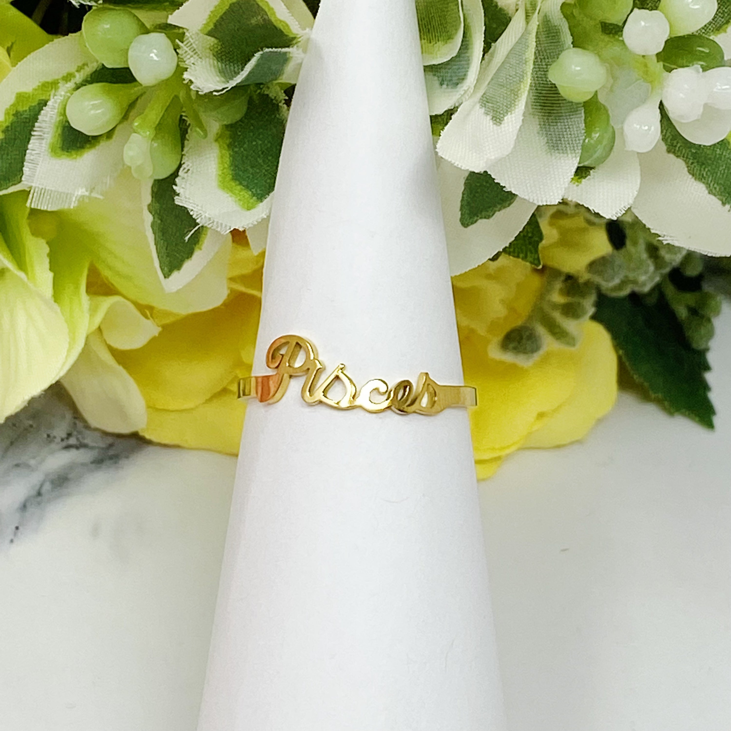 A beautifully crafted adjustable ring featuring delicately scripted zodiac signs, made of stainless steel and 18K gold plated.