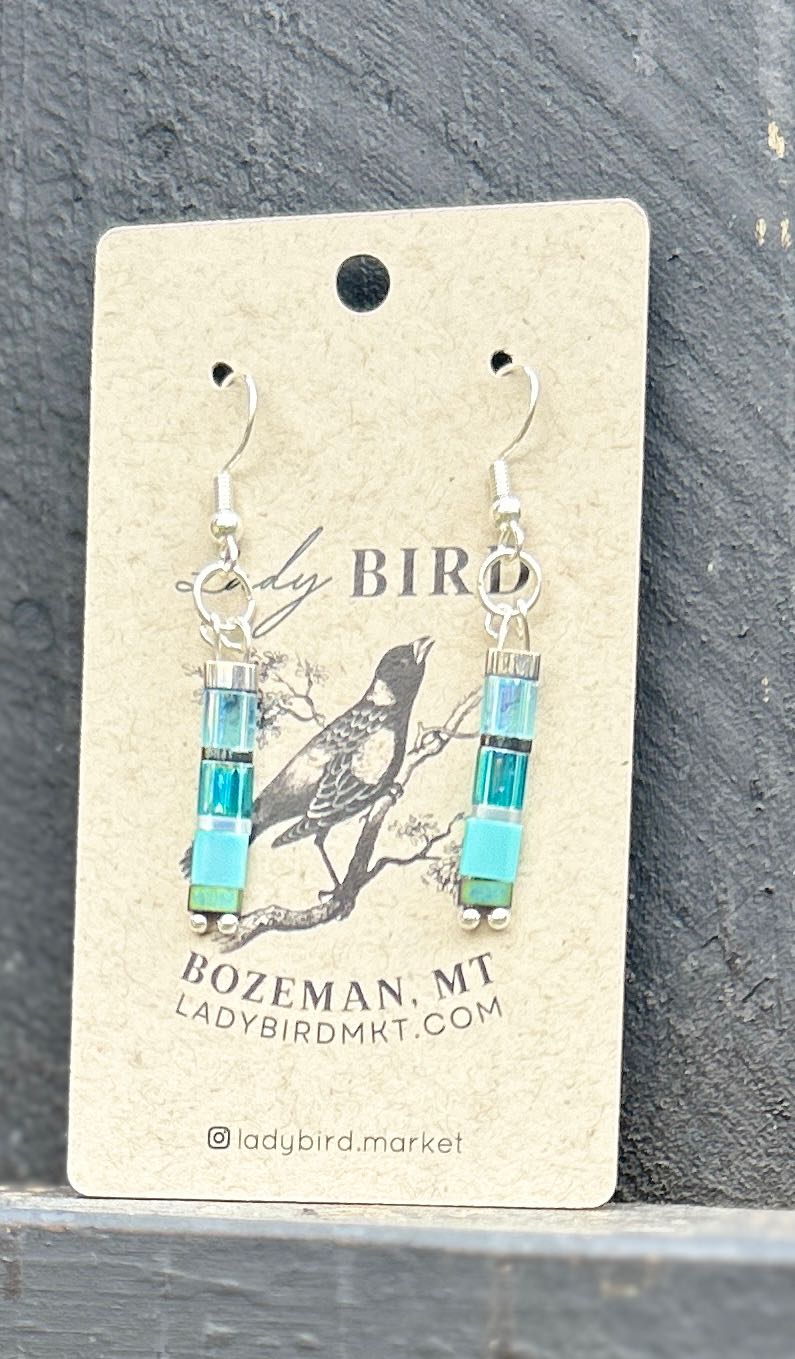 A pair of Sea Glass Blues & Silver Tila Bead Earrings featuring vibrant blue tila beads and silver accents, showcasing a bohemian style.