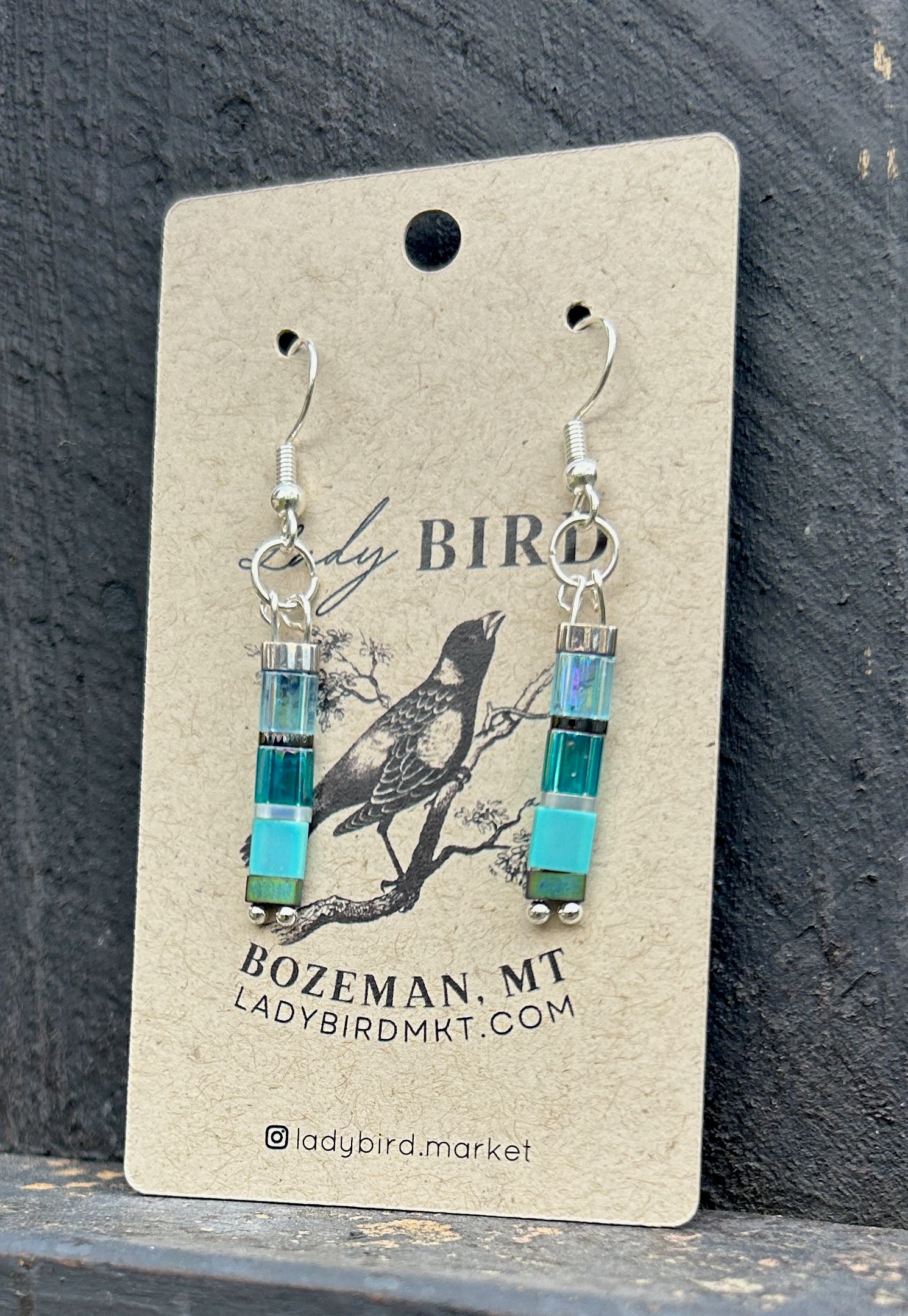 A pair of Sea Glass Blues & Silver Tila Bead Earrings featuring vibrant blue tila beads and silver accents, showcasing a bohemian style.