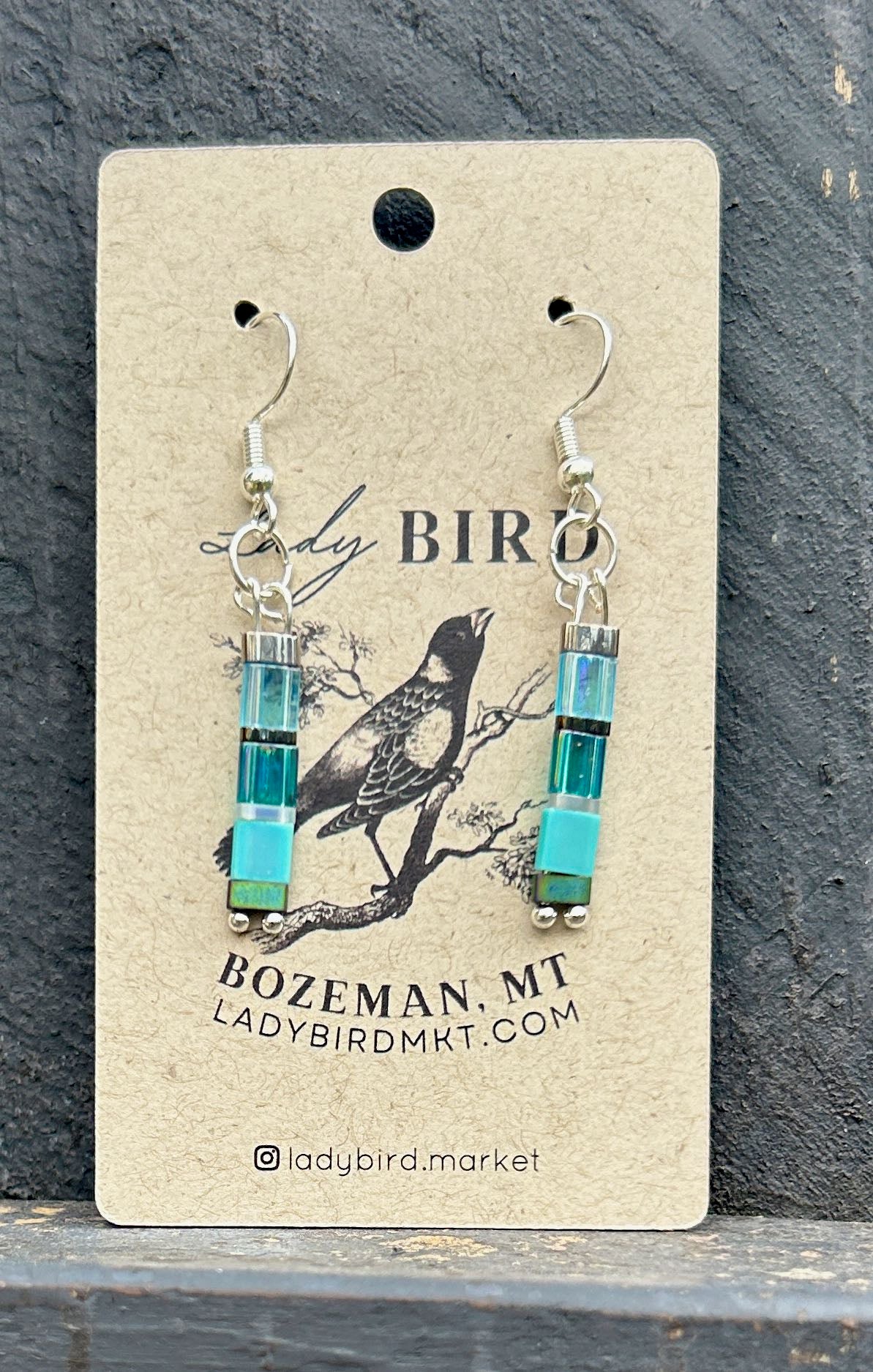 A pair of Sea Glass Blues & Silver Tila Bead Earrings featuring vibrant blue tila beads and silver accents, showcasing a bohemian style.