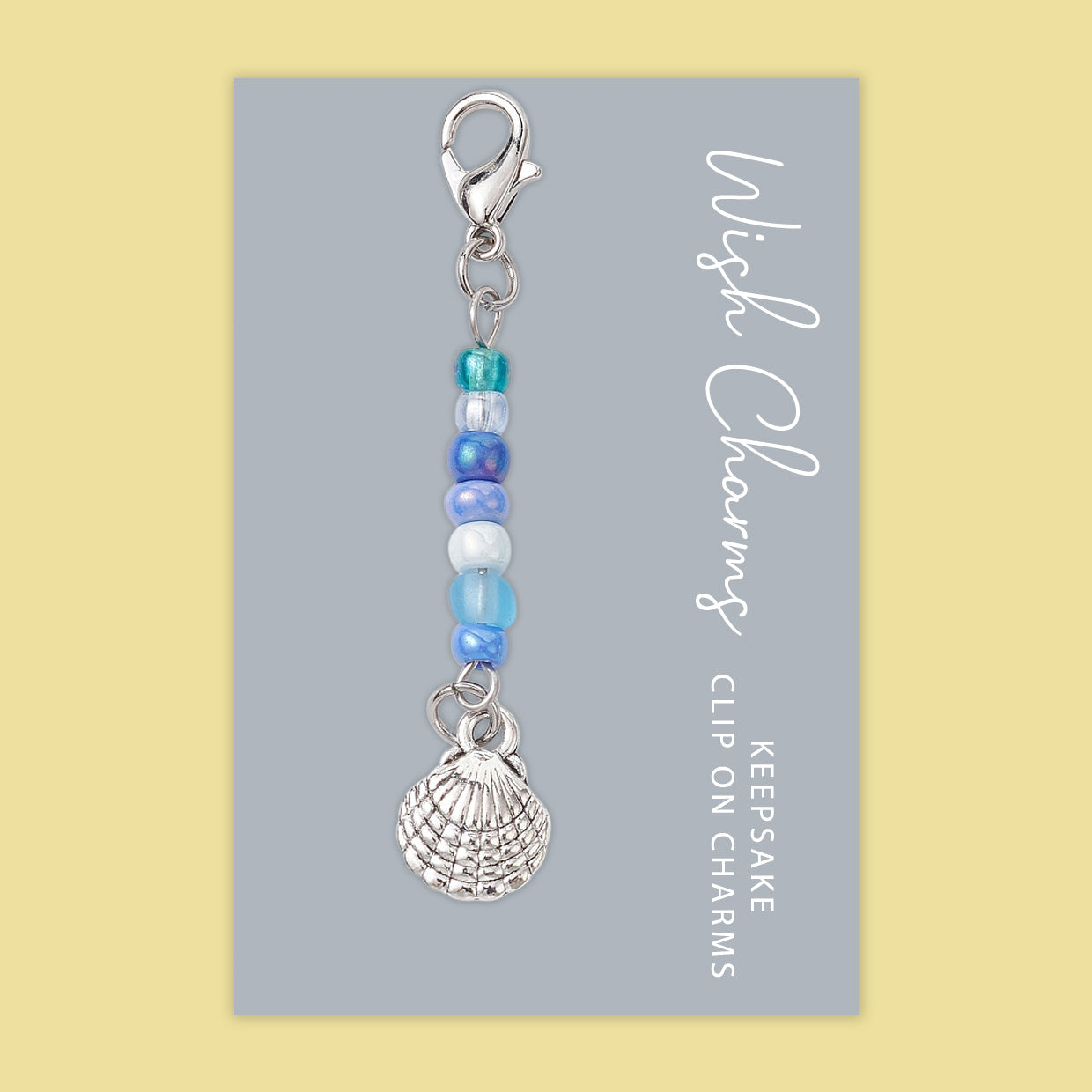 A beautiful Sea Shell Wish Charm featuring glass beads and Tibetan silver, elegantly displayed on a glossy card.