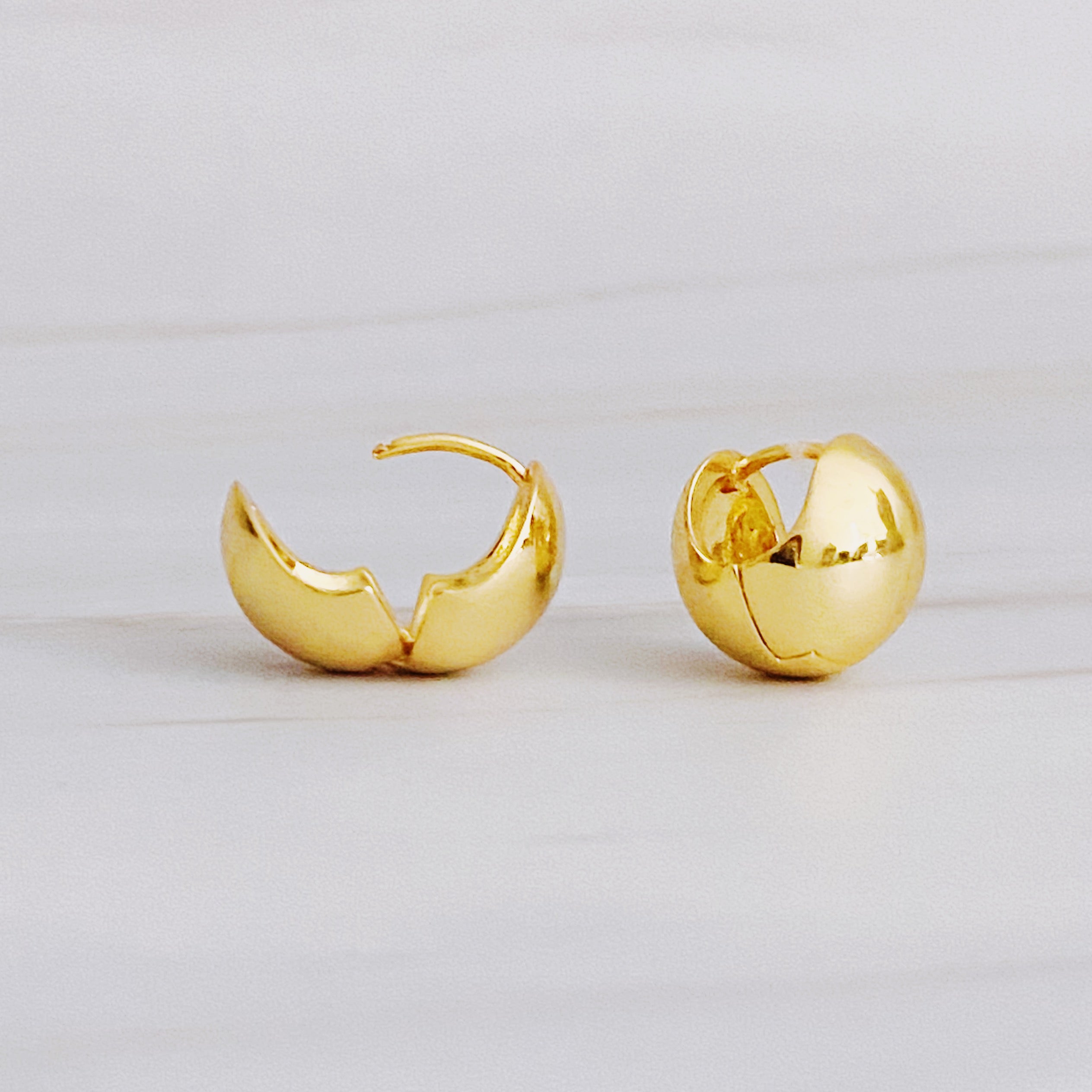 A pair of Seamlessly Round Stud Hoop Earrings in polished gold and silver finishes, showcasing their elegant and chic design.